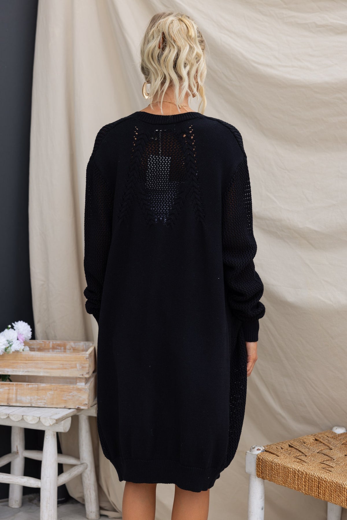 Back view of a black Lorendo cardigan with a longline fit and knit material, showcasing its relaxed style and unique design.