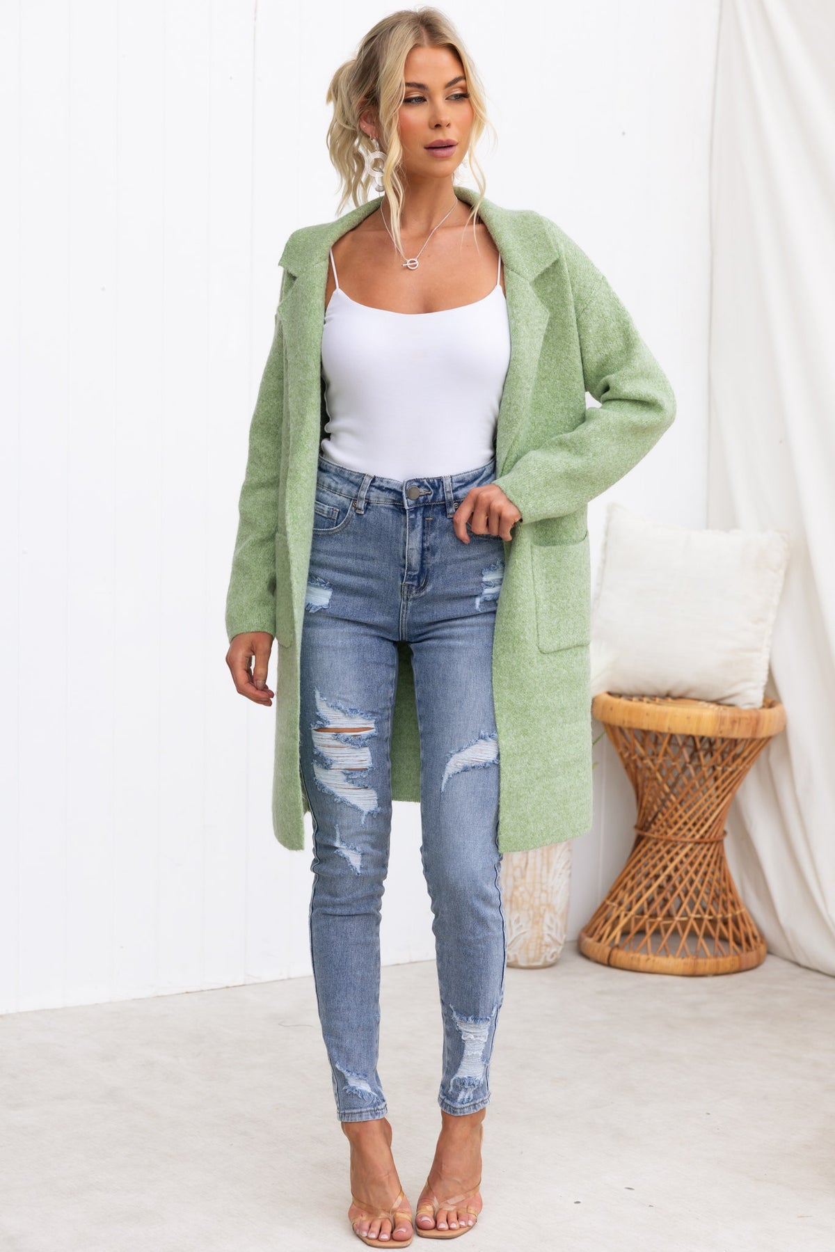 Model wearing a green Sarlia Cardigan over a white top and ripped jeans, styled for a casual look.