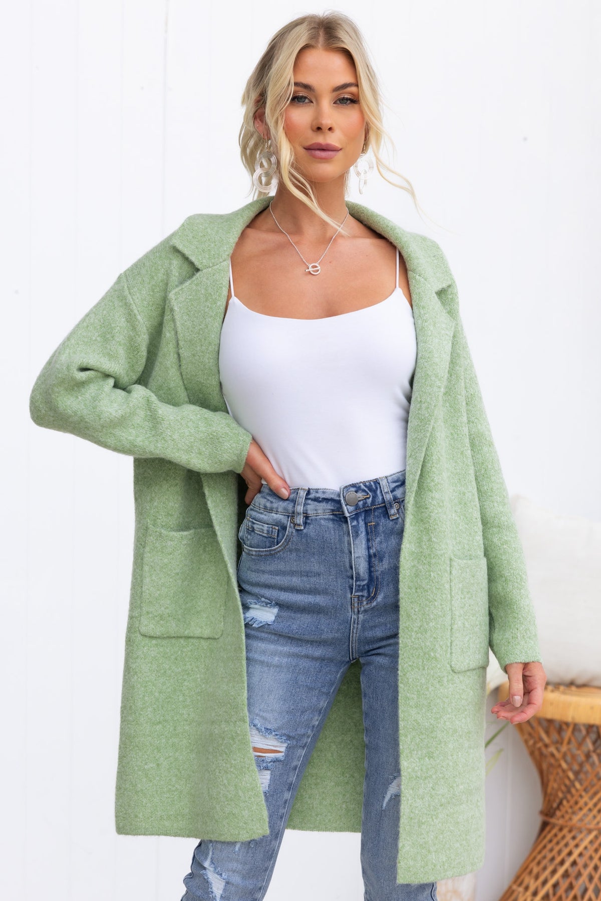 Model wearing a light green Sarlia cardigan with pockets over a white top and distressed jeans.