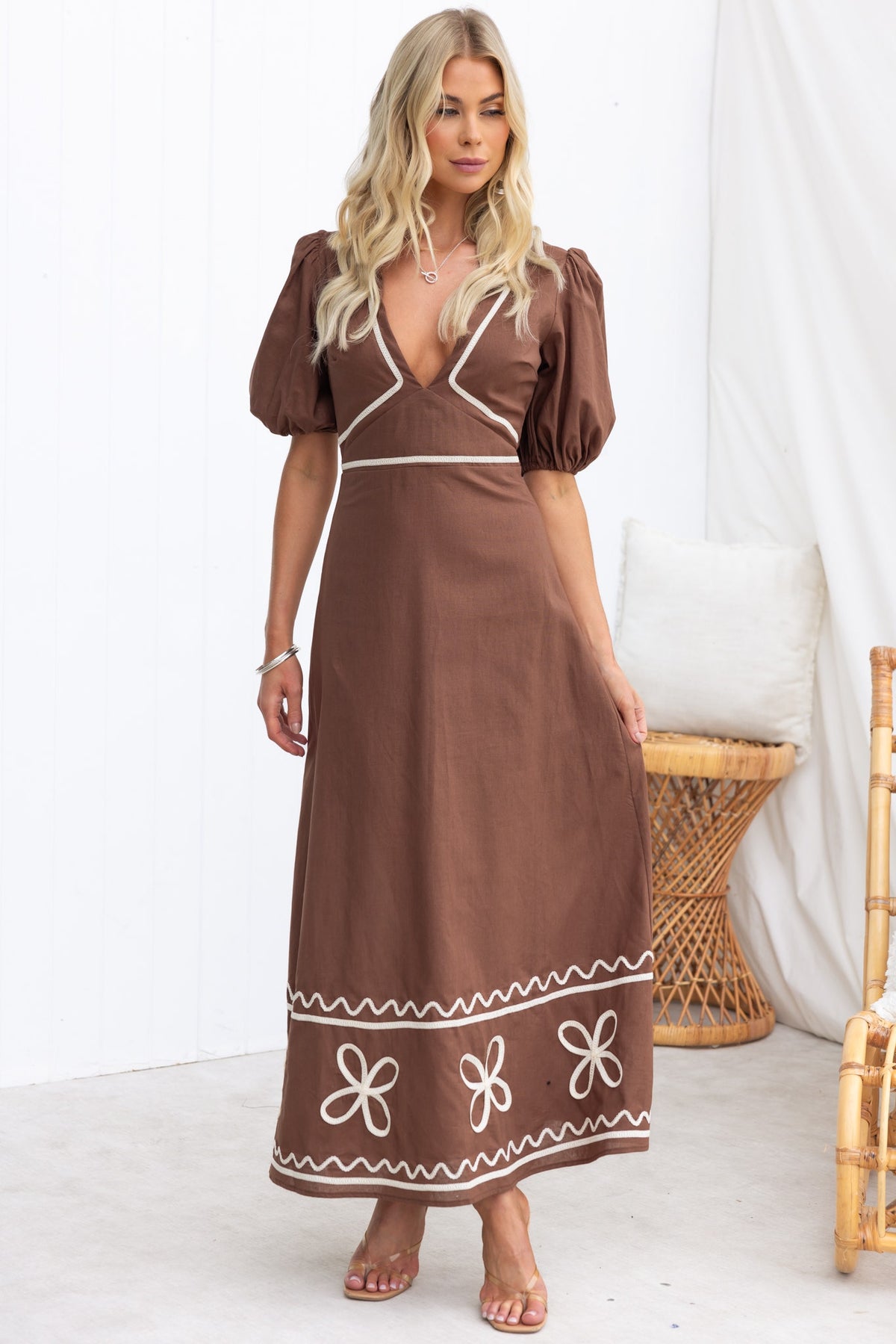 Azurra Maxi Dress in brown with V-neckline and puff sleeves, featuring floral embroidery along the hem.