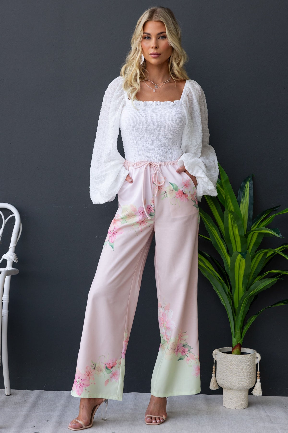 Model wearing Joey Top with square neckline and floral pants, surrounded by indoor greenery.