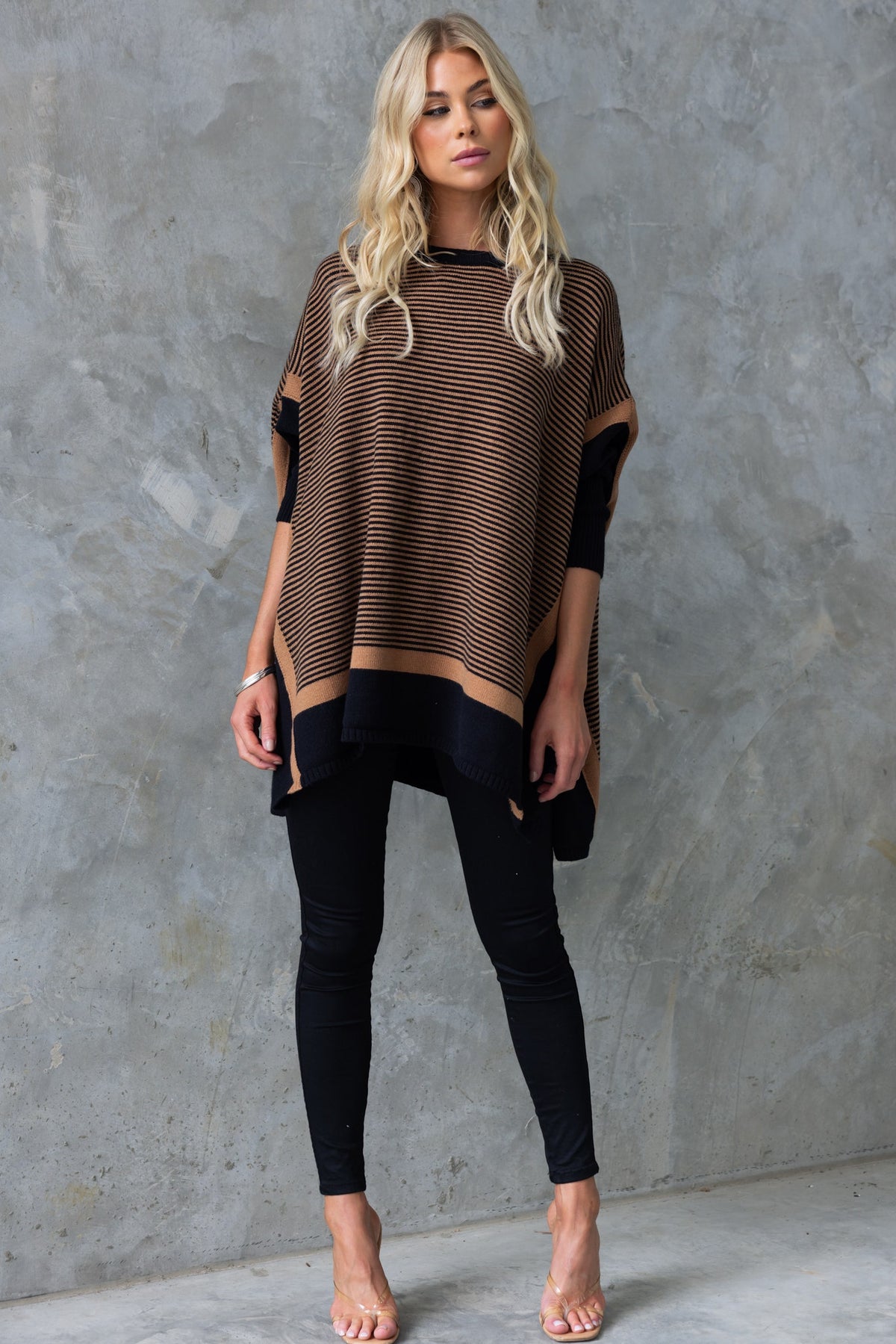 Model wearing a striped Journey Jumper with batwing sleeves styled with black leggings.