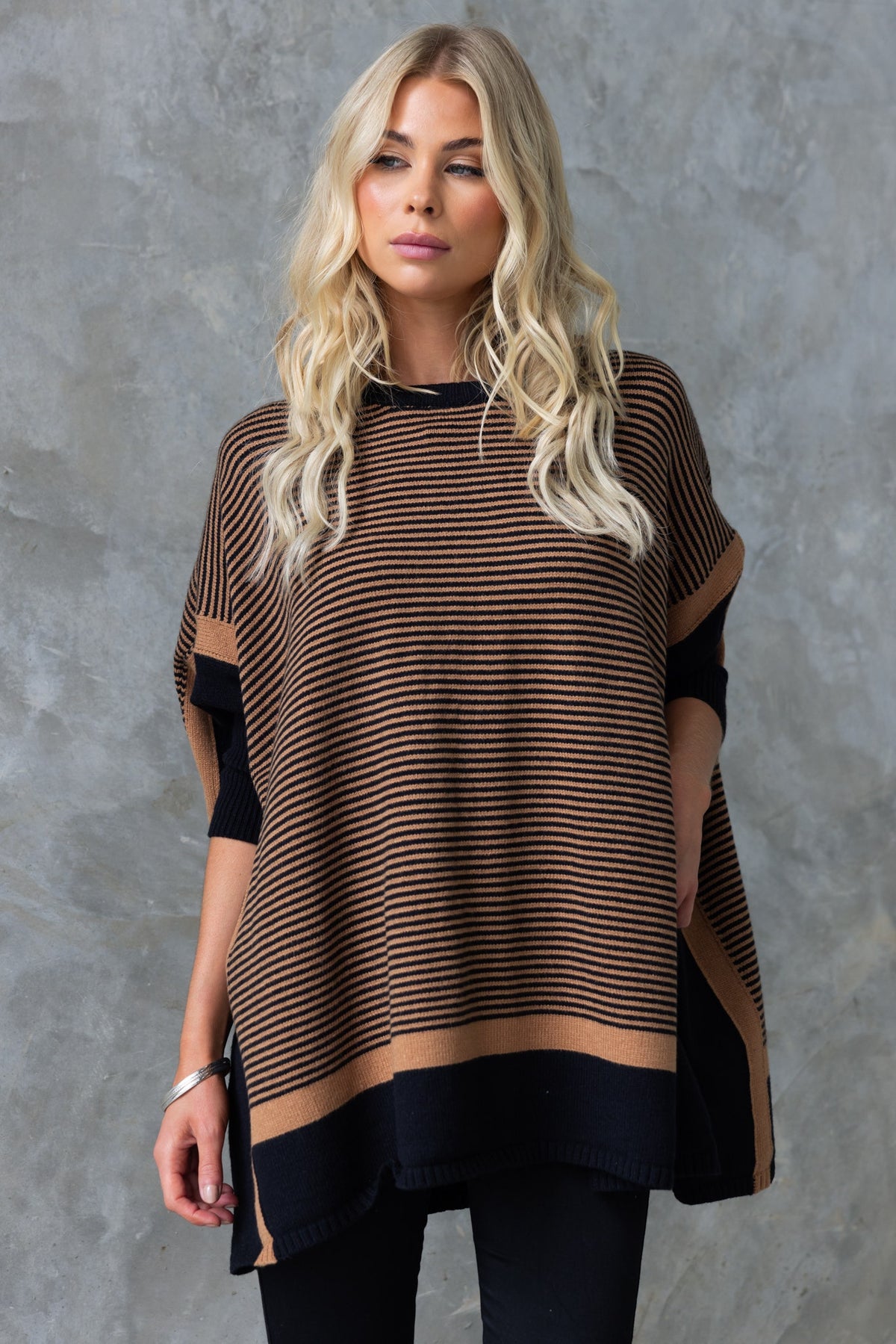 Woman wearing a striped batwing sleeve jumper in brown and black, showcasing a relaxed oversized fit.