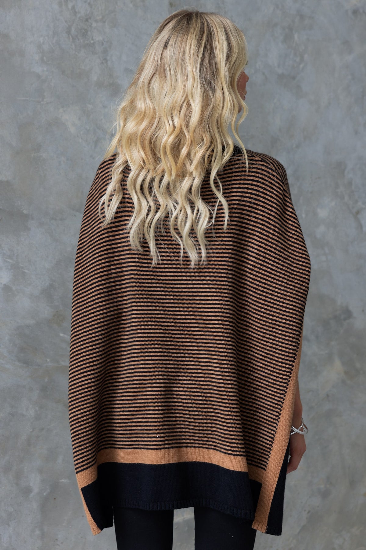 Woman wearing a striped brown and black Journey Jumper with batwing sleeves, viewed from the back.