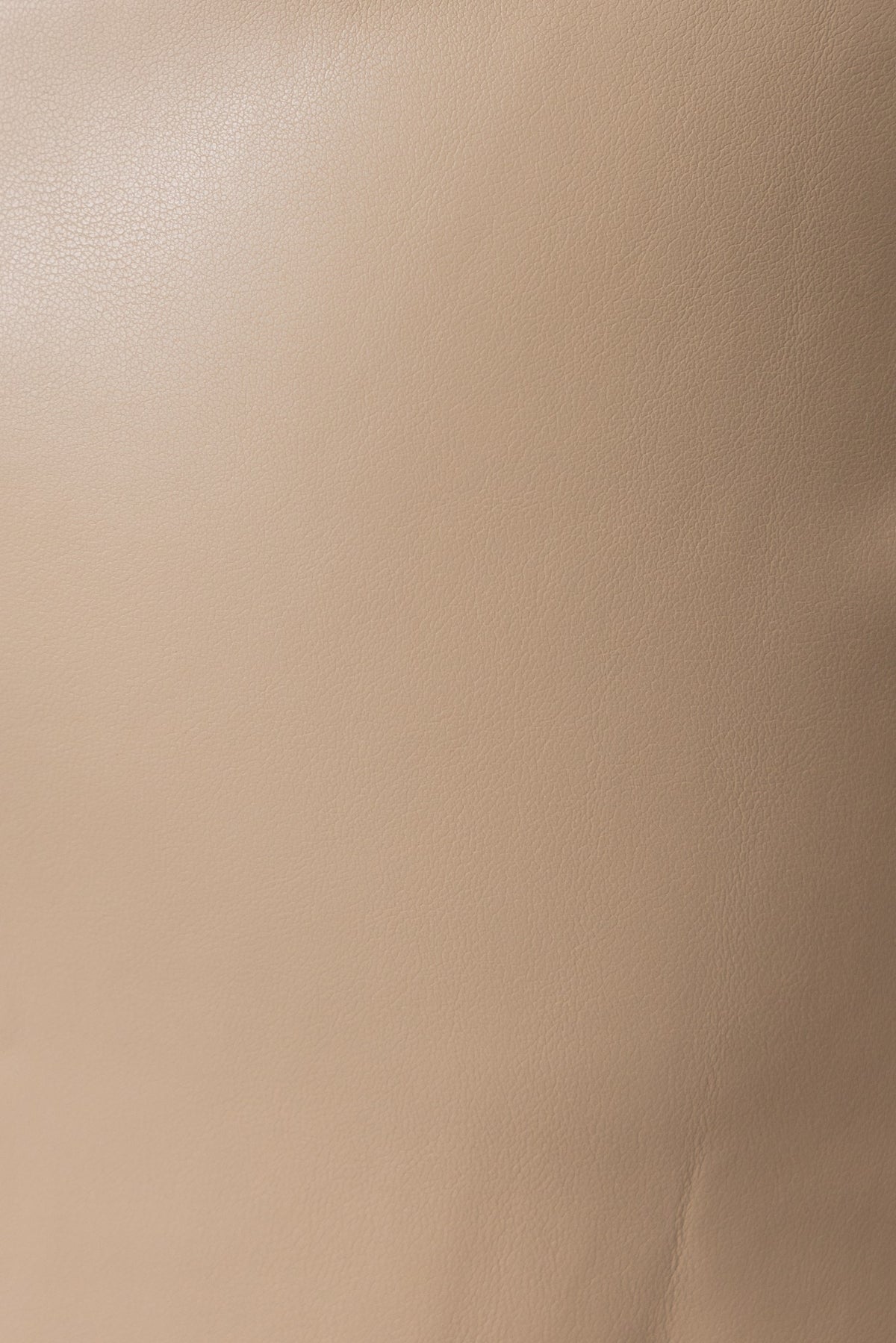 Close-up of a smooth faux leather material in beige, showcasing its texture and quality.