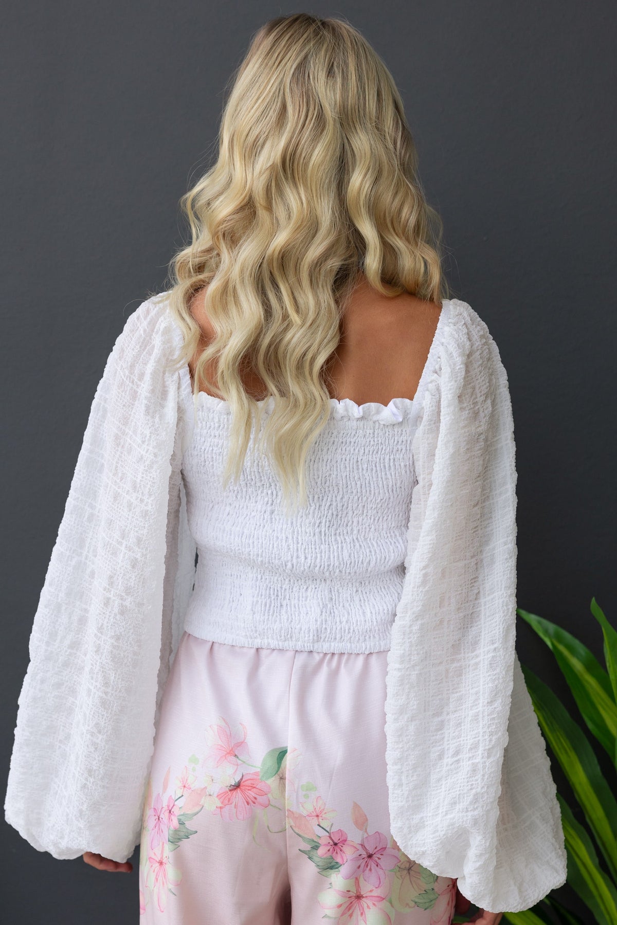 Back view of a woman in a white Joey Top with textured fabric and puff sleeves, paired with floral pajama pants.