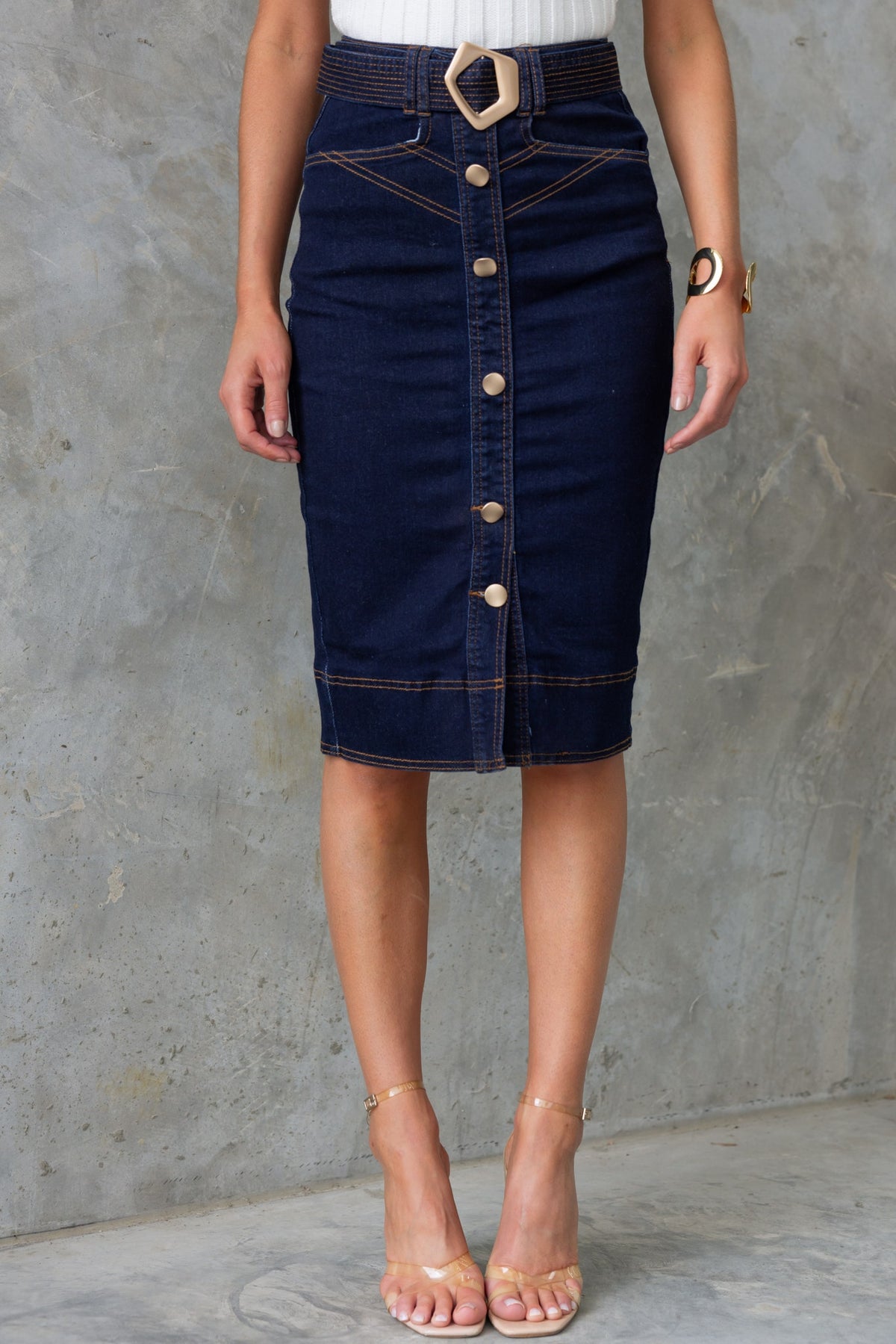 Ovida denim skirt with mid-high waist, removable belt, and button detailing, styled with a model on a textured background.