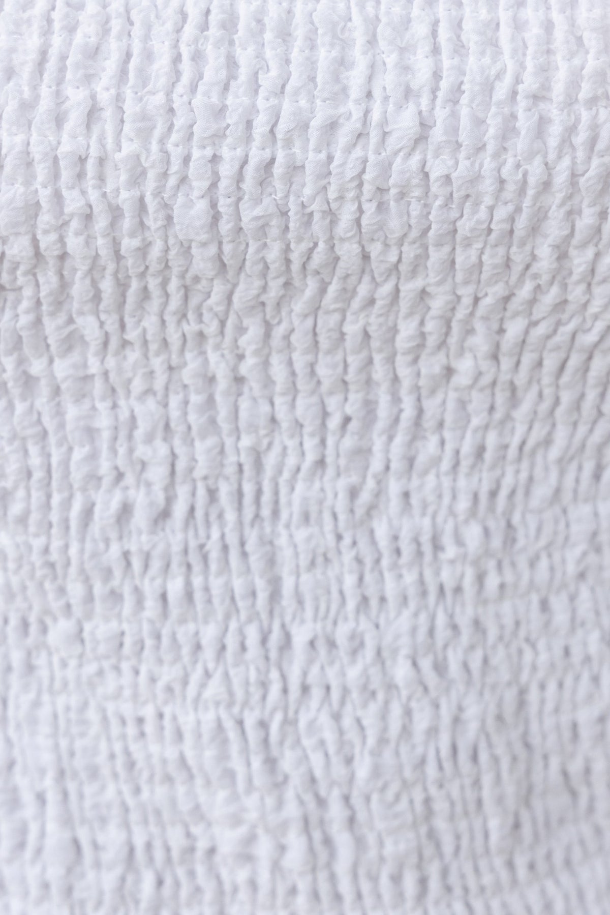 Close-up of textured white fabric showcasing the detailed smocking technique used in the Joey Top.