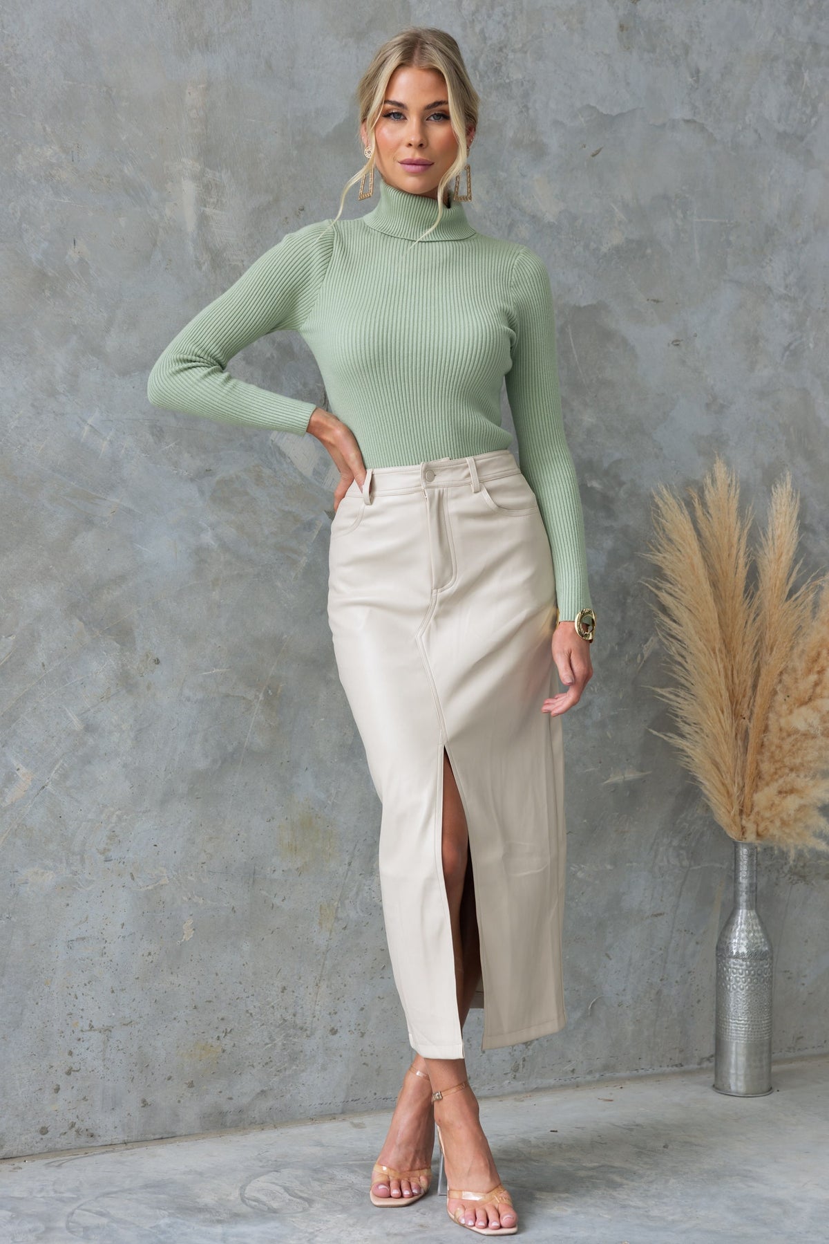 Model wearing the Narla Top in ribbed knit, styled with a sleek cream skirt against a textured background.