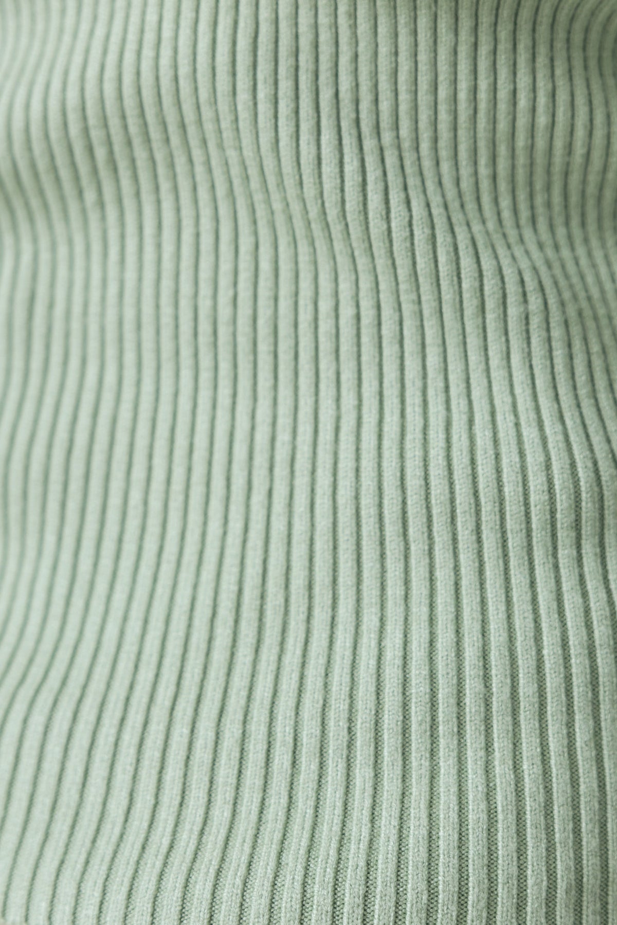 Close-up of ribbed knit fabric in soft green, showcasing stretchy texture perfect for the Narla Top.