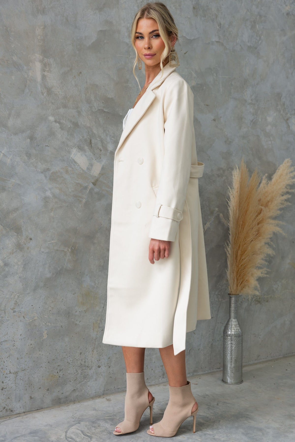 Lansen Coat in cream, longline fit with collar, button-up front, pockets, and removable tie, worn by model.