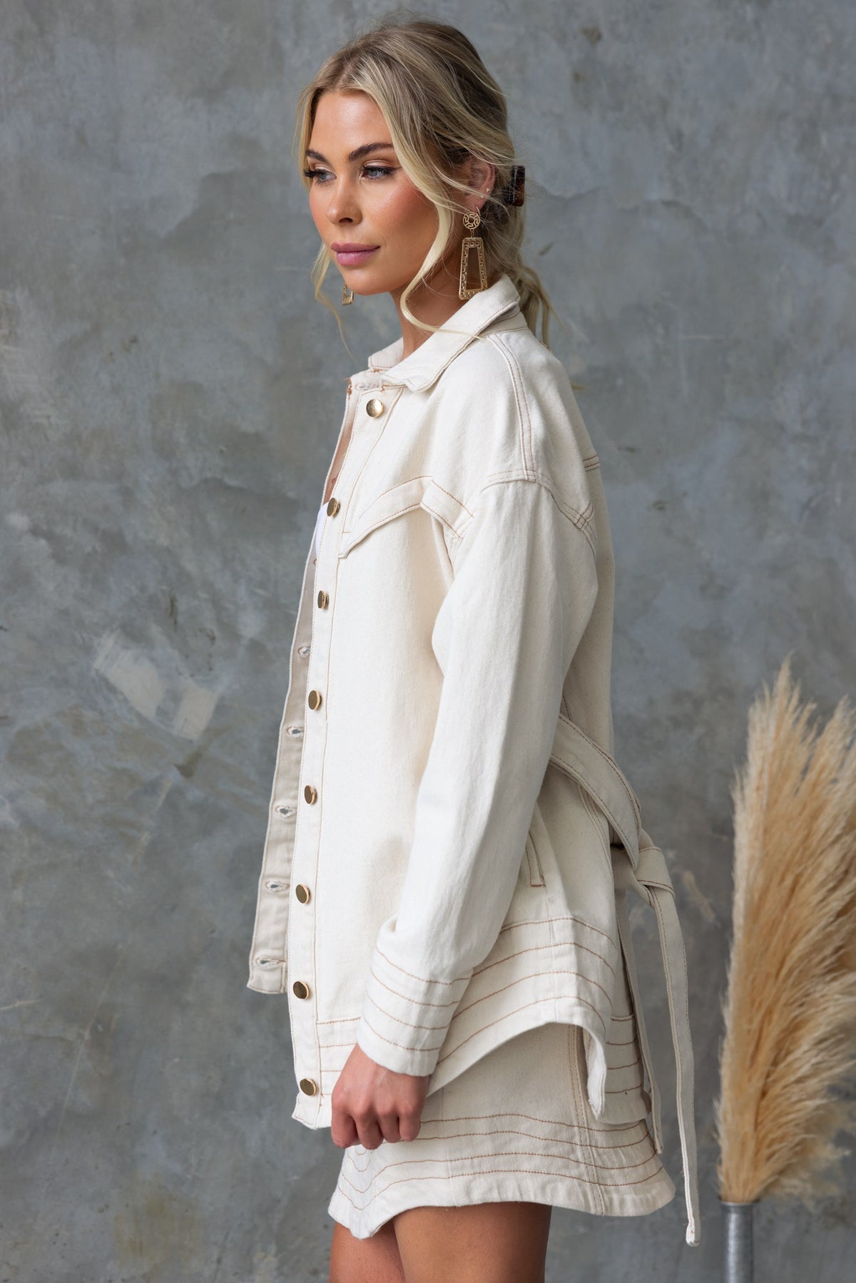 Model showcasing a Kaylen Denim Shacket in cream, featuring a button-up front, collar, and removable tie.