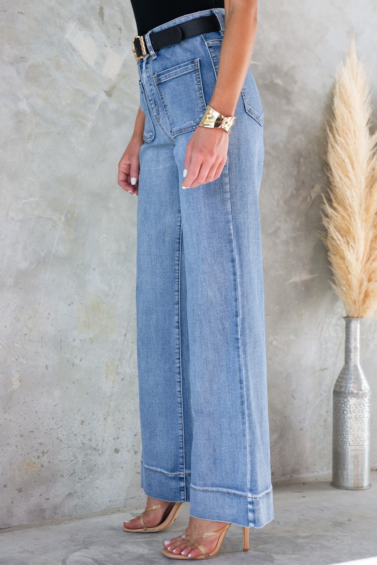 Side view of a woman wearing high-waisted denim jeans with straight leg fit, styled with a black top and accessories.