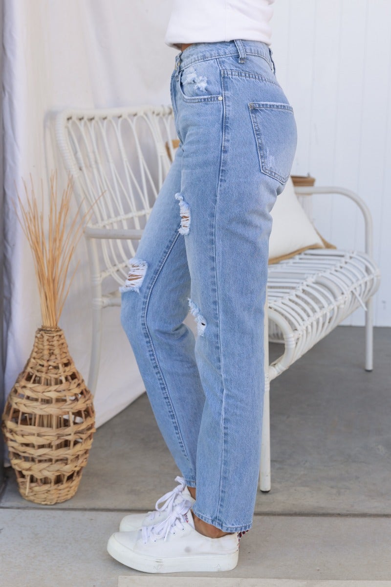 Side view of All The Time Jeans, distressed light blue denim with rips, mid-high waist, styled with white sneakers.