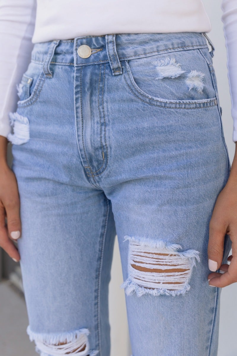 Mid-high waist distressed denim jeans with rips at the front, perfect for casual wear.