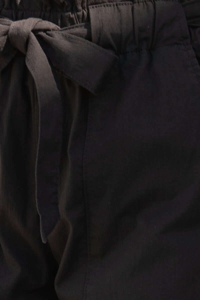 Close-up of Zol Pants featuring elastic waistband and removable fabric belt in black.