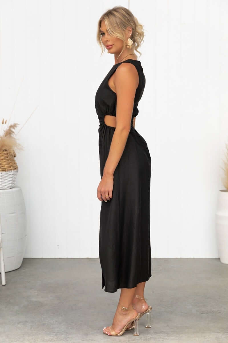 Stylish woman in Rozita Midi Dress, a black linen blend dress with side cut-outs and front slit, perfect for summer outings.