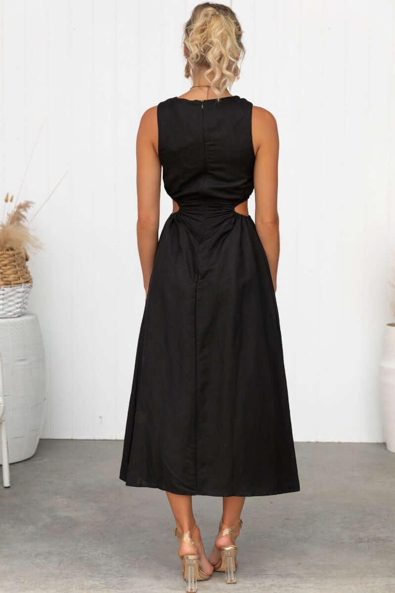 Back view of Rozita Midi Dress in black linen blend with cut-out elastic at sides and slit at front.