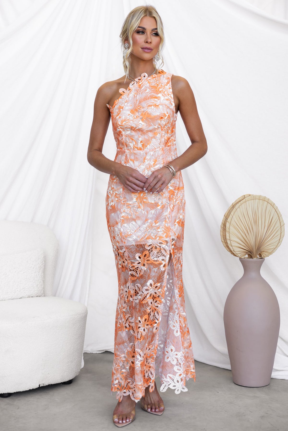 Racha Maxi Dress in orange floral print, featuring a one-shoulder design and front split, styled for elegant occasions.