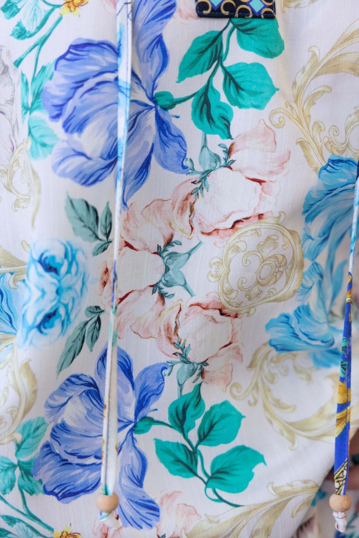 Close-up of floral print fabric featuring blue and pink flowers, showcasing tie detail and vibrant colors.