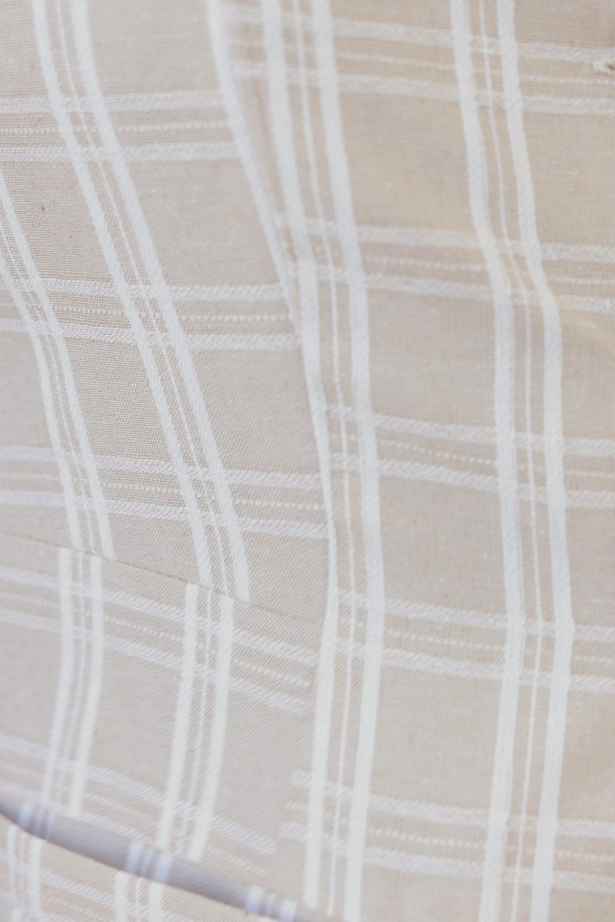 Textured fabric close-up showcasing a light beige linen blend with subtle white plaid pattern for Bexley Pants.