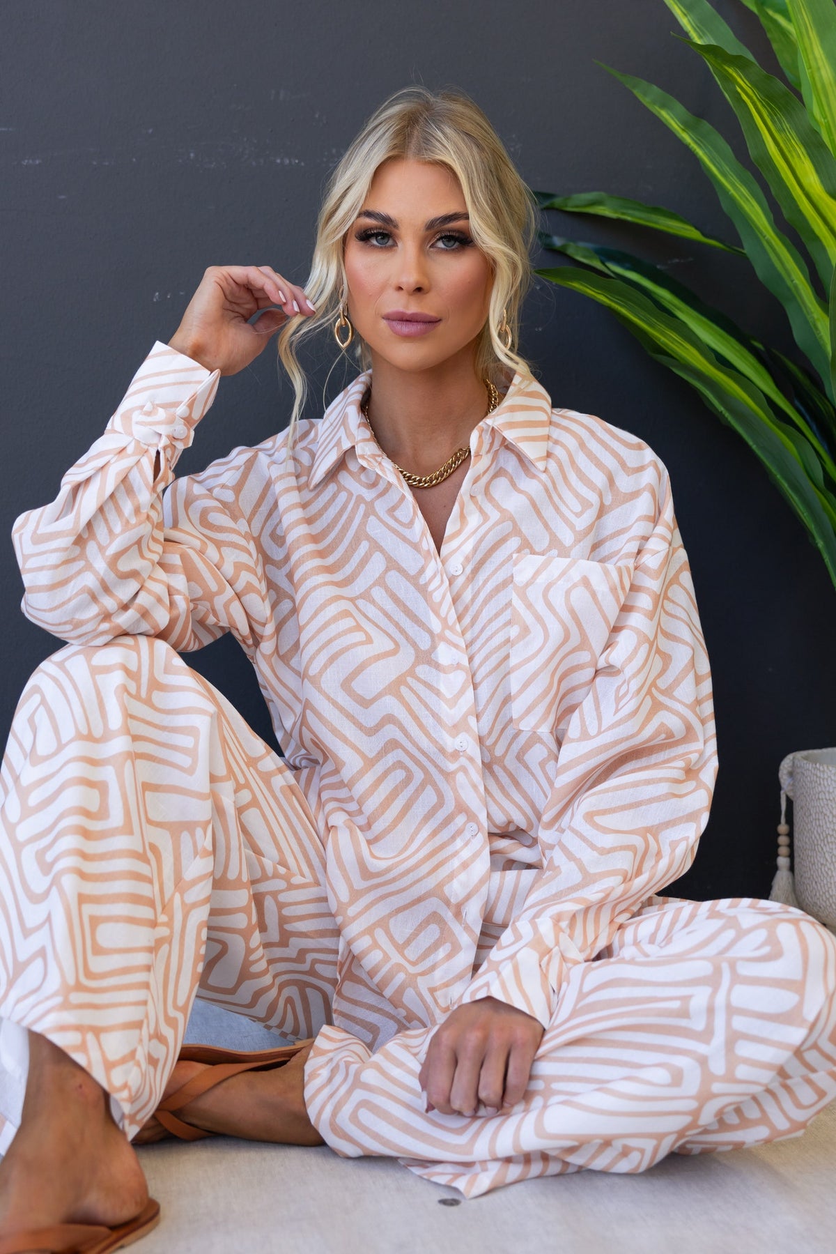 Model wearing a Tari Shirt, a relaxed-fit cotton shirt with a unique pattern, paired with stylish accessories and a plant backdrop.