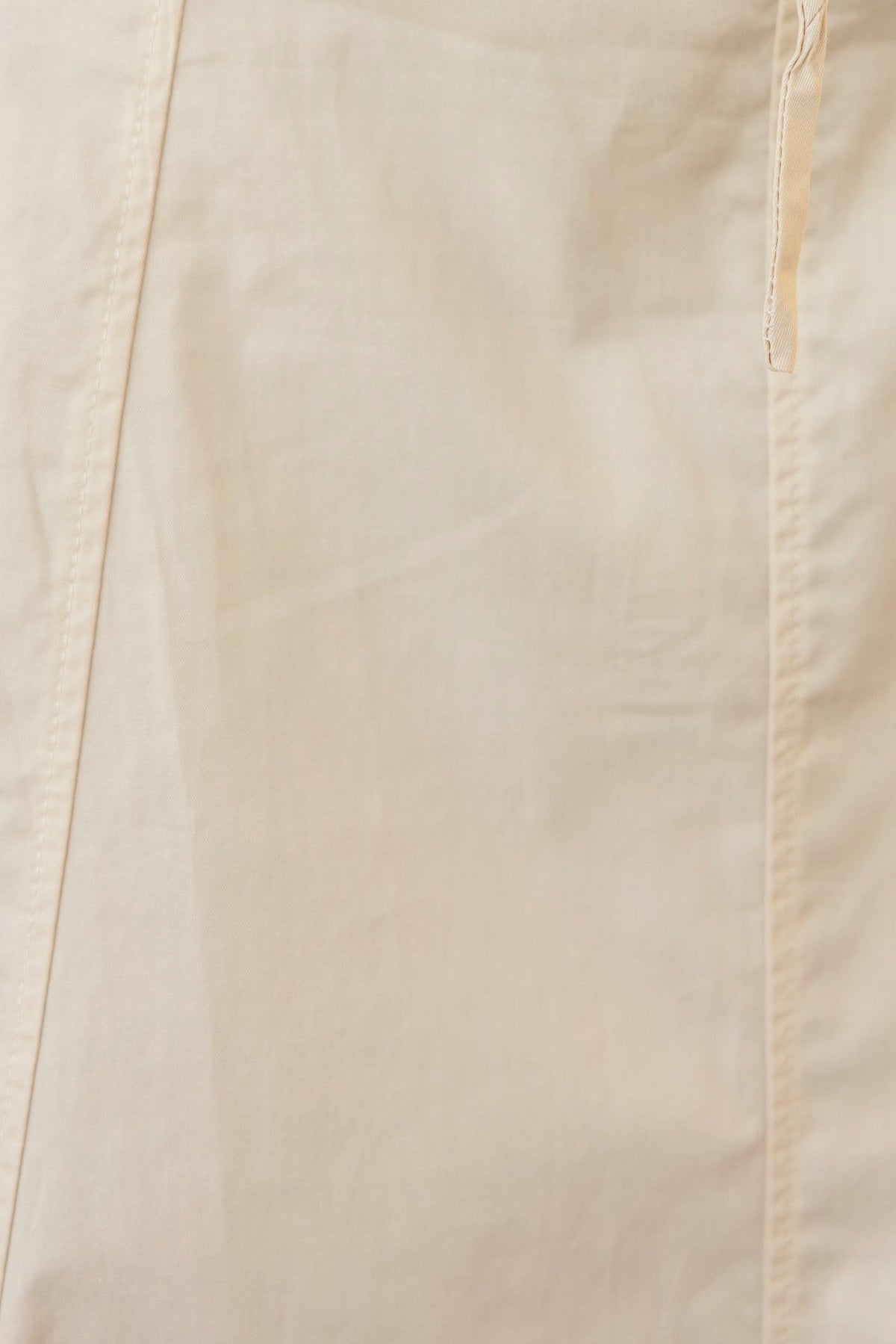 Close-up of a cream-colored fabric showcasing its smooth texture and seam details for the Crave Set.