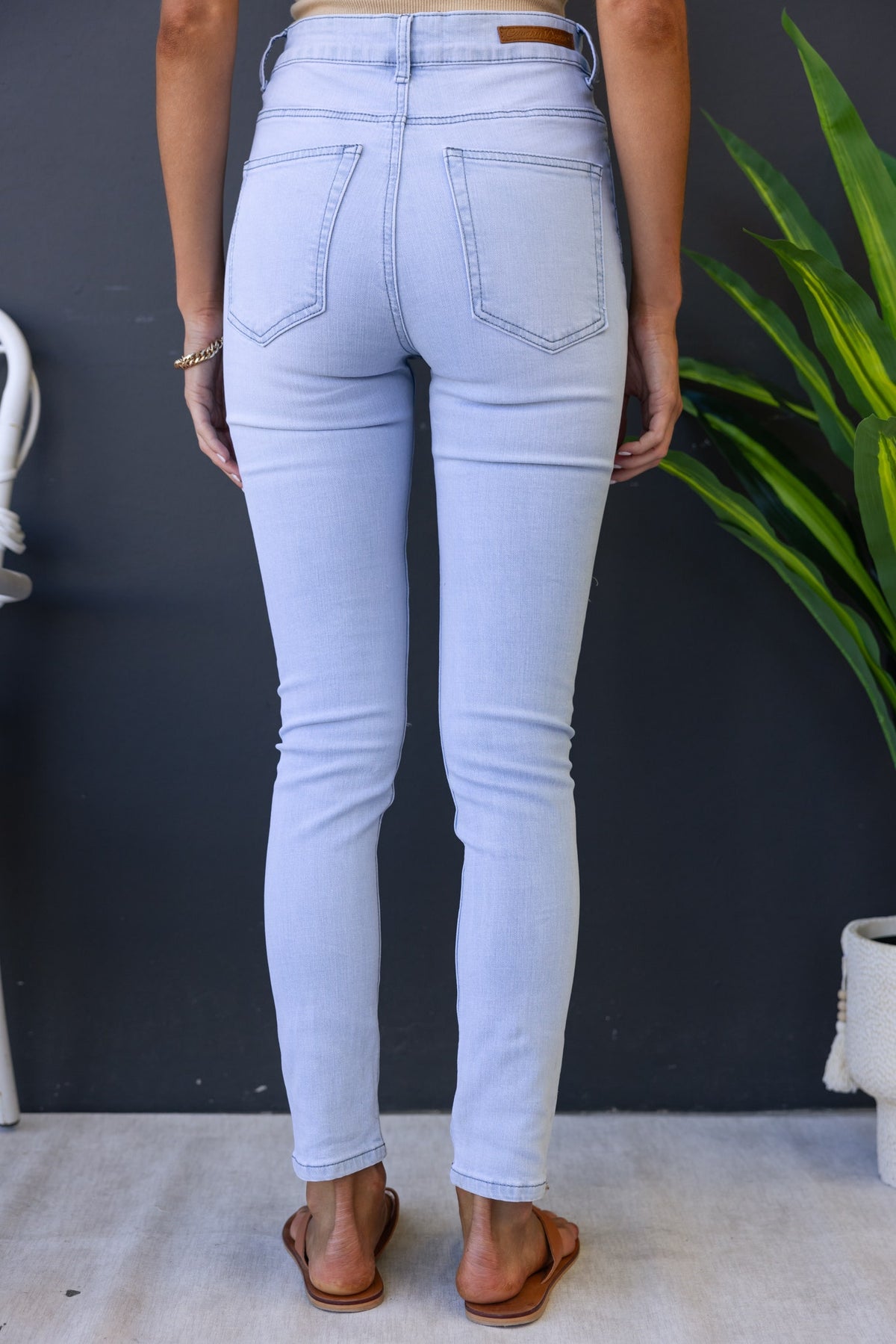 Light blue Milos jeans with a mid-high waist and distressed rips, showcasing back view and pockets.