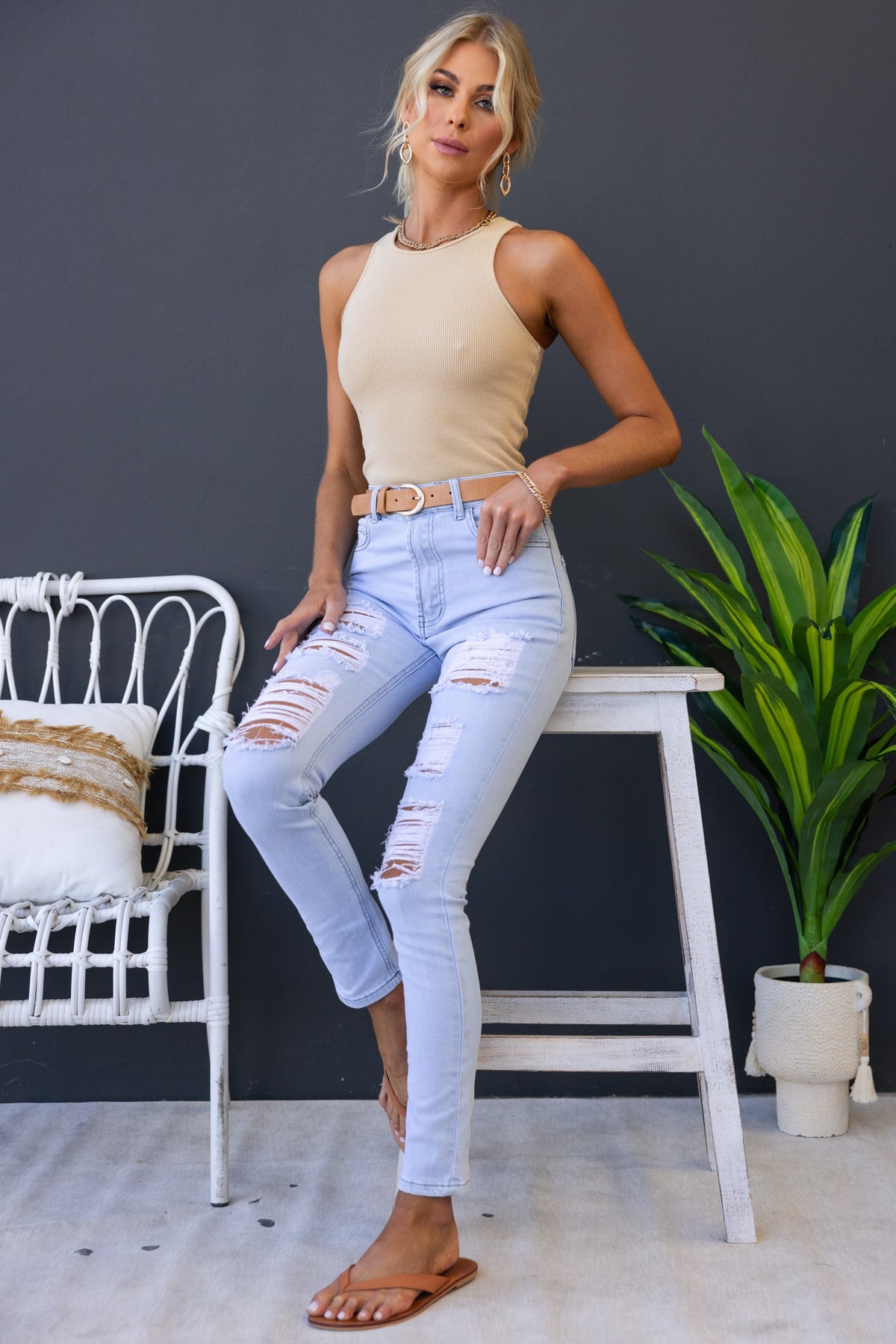 Model wearing Milos Jeans, light blue distressed denim, mid-high waist, paired with a simple tank top and sandals.
