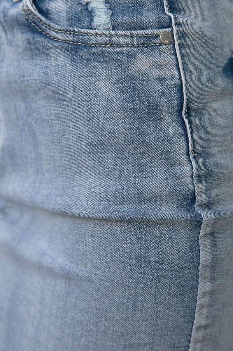 Close-up of Nice For What Skirt showing distressed details with pockets and raw hem in light blue denim.
