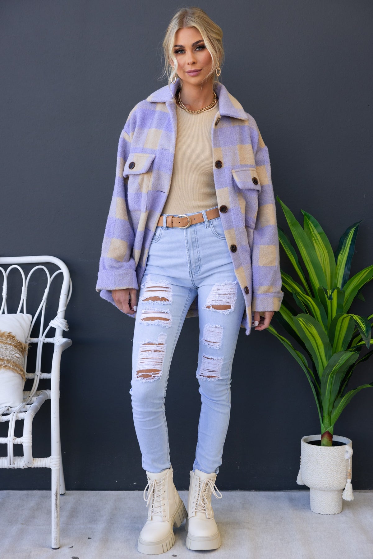 Fashionable woman in oversized purple and beige checkered shacket paired with distressed jeans and stylish boots.