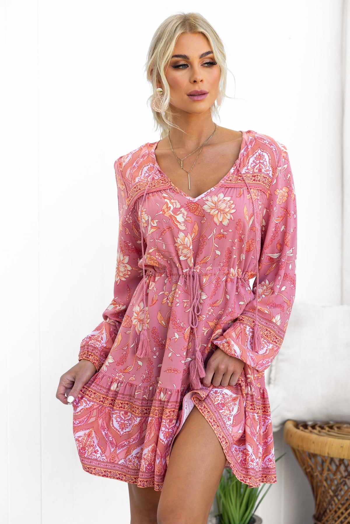 Eliana Dress in pink with floral pattern, featuring a V-neckline and drawstring waist, styled elegantly in a relaxed fit.