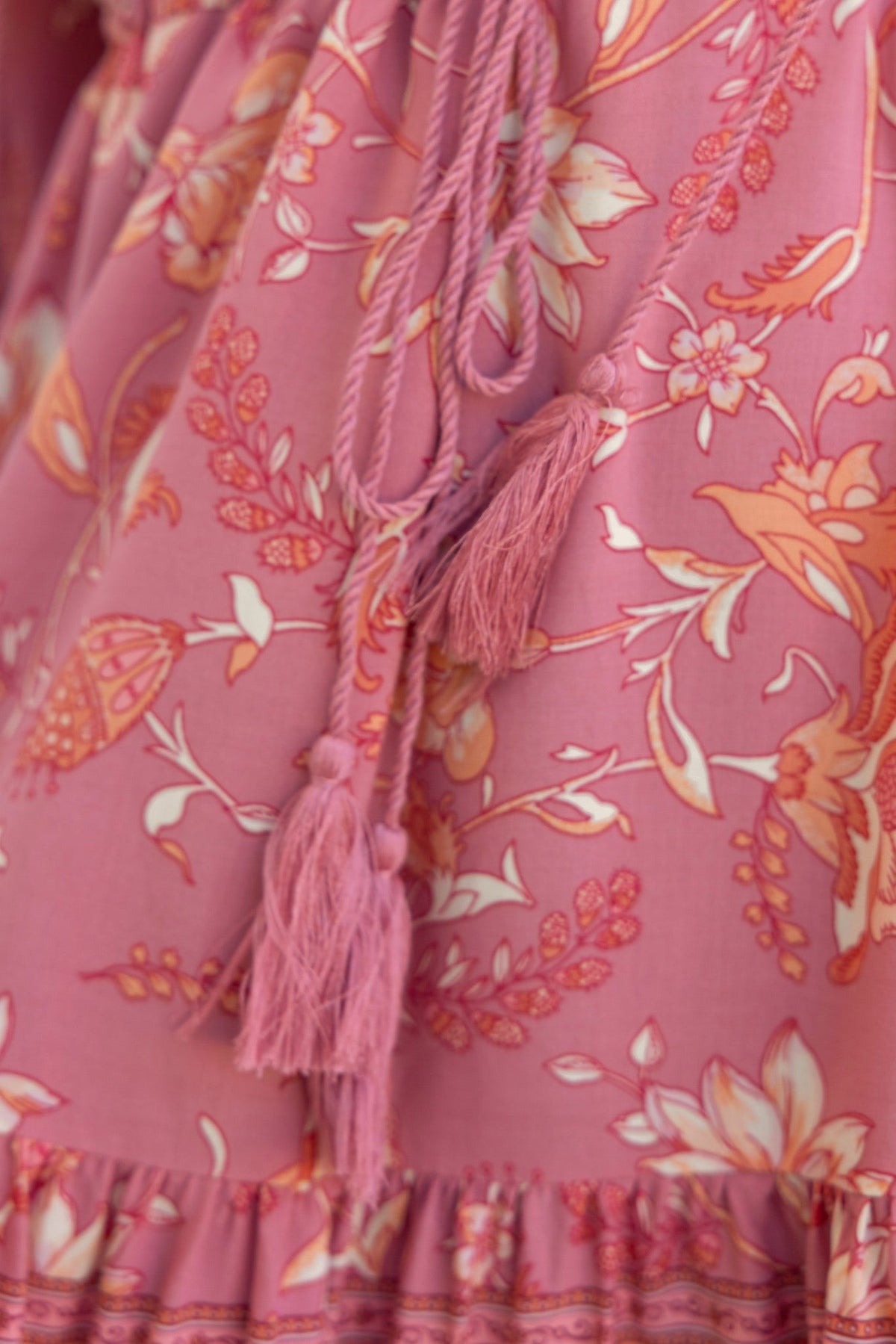 Close-up of Eliana Dress in pink floral pattern featuring tassels and drawstring detail.