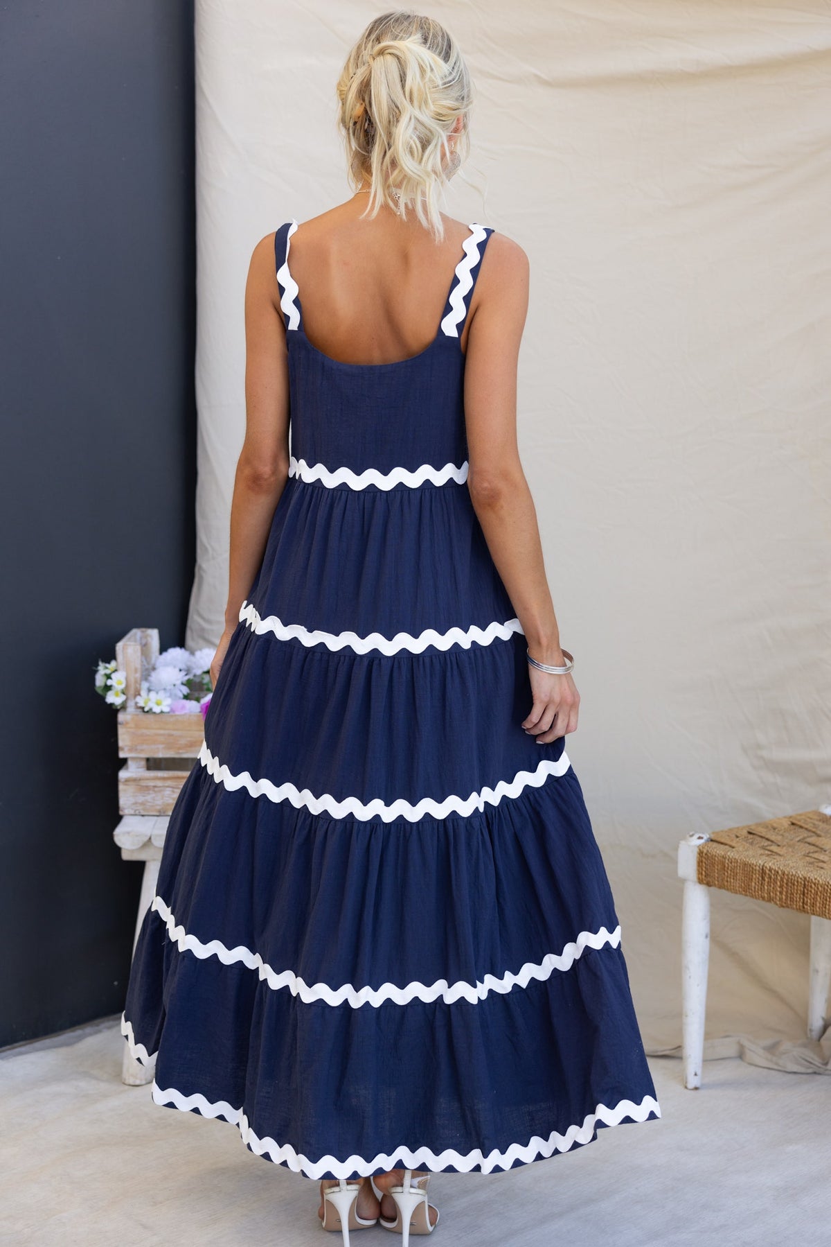 Back view of a navy Nori maxi dress with white ruffle detailing, showcasing a relaxed fit and cotton material.