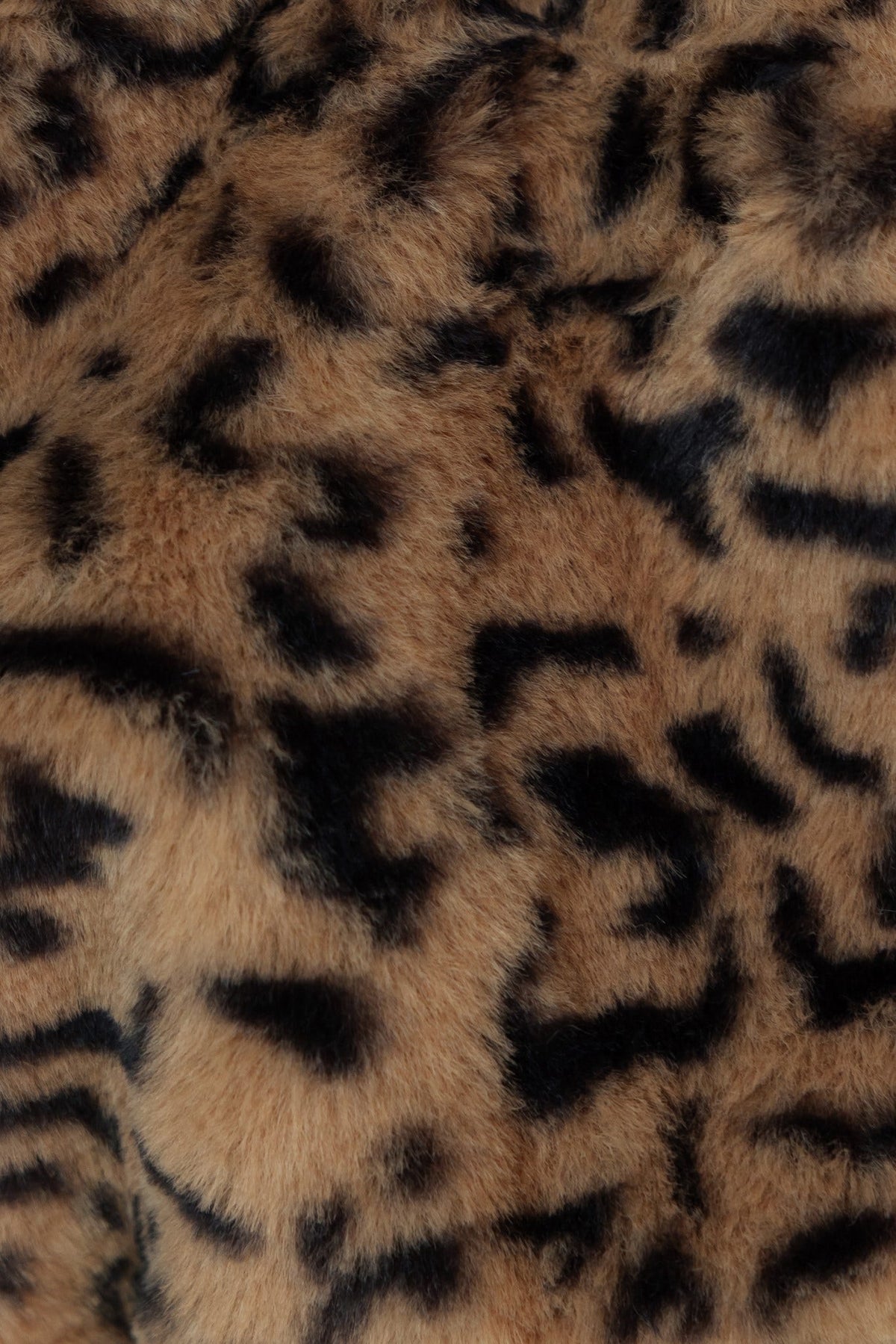 Close-up of soft leopard print fabric with a fuzzy texture in brown and black, ideal for stylish apparel.