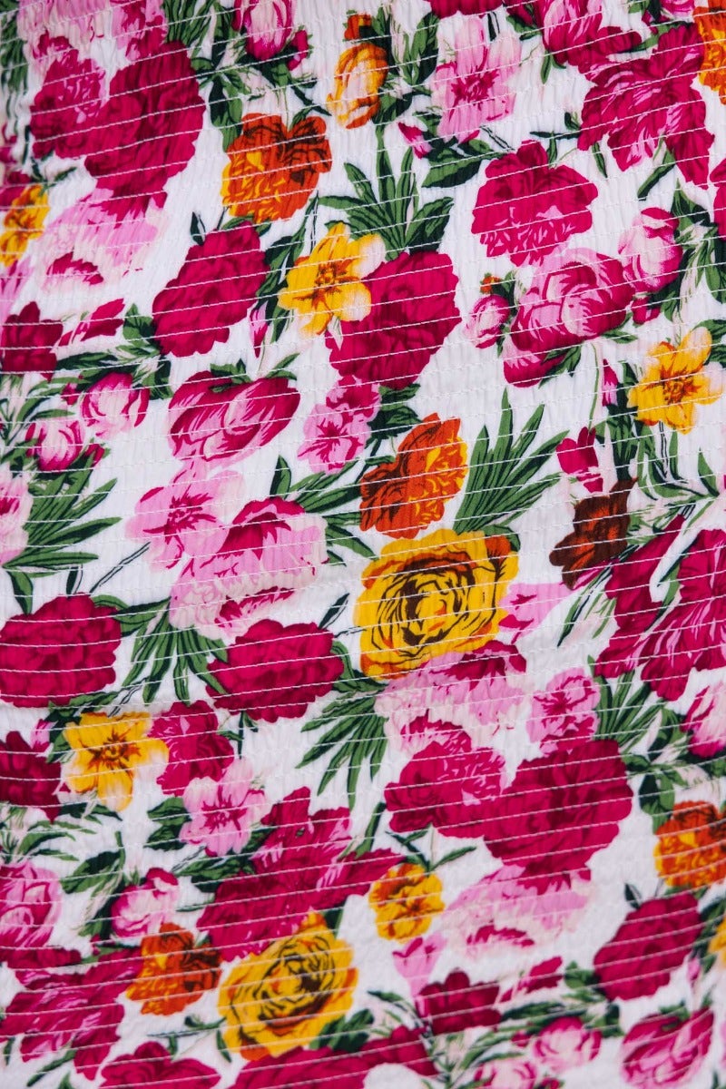 Close-up of vibrant floral pattern in pink, orange, and yellow on a white fabric, perfect for the Gwenna Midi Dress.