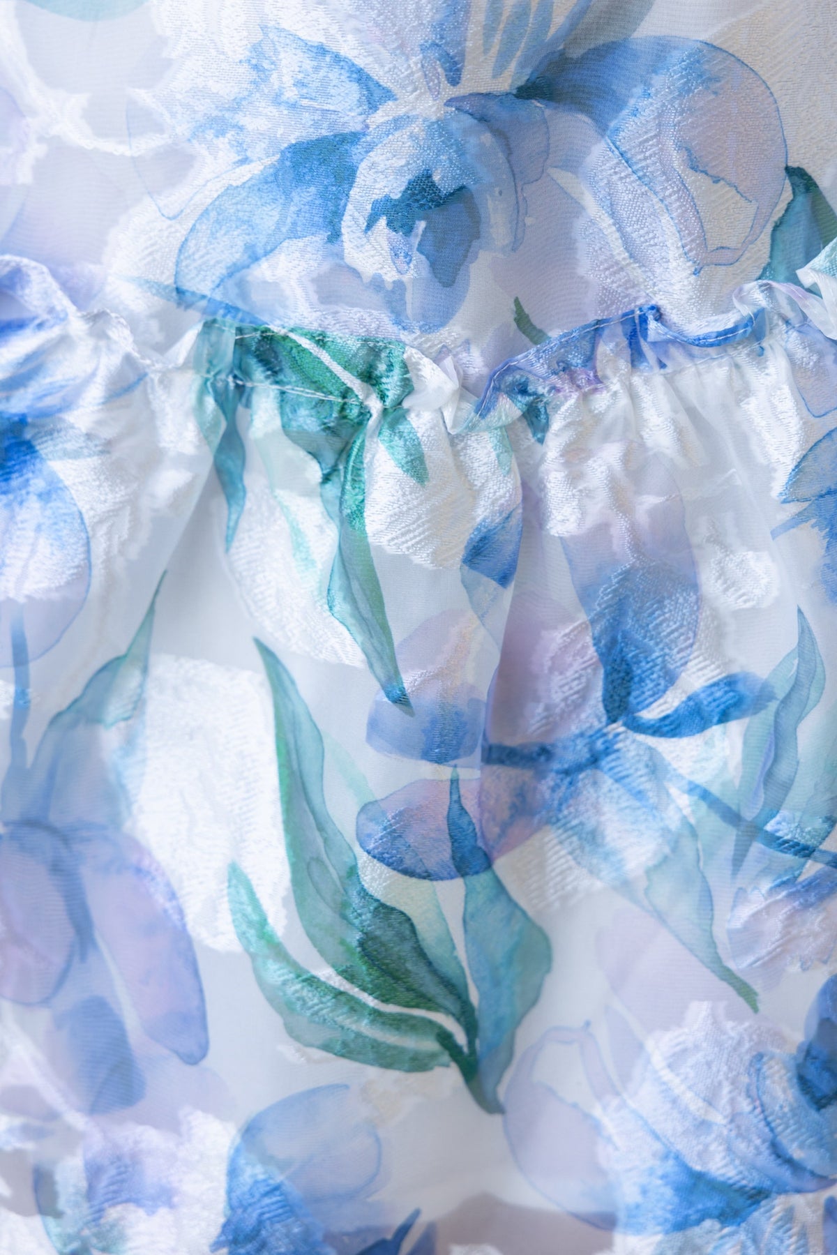 Close-up of Wisteria dress fabric featuring delicate blue floral pattern and ruffled detail.