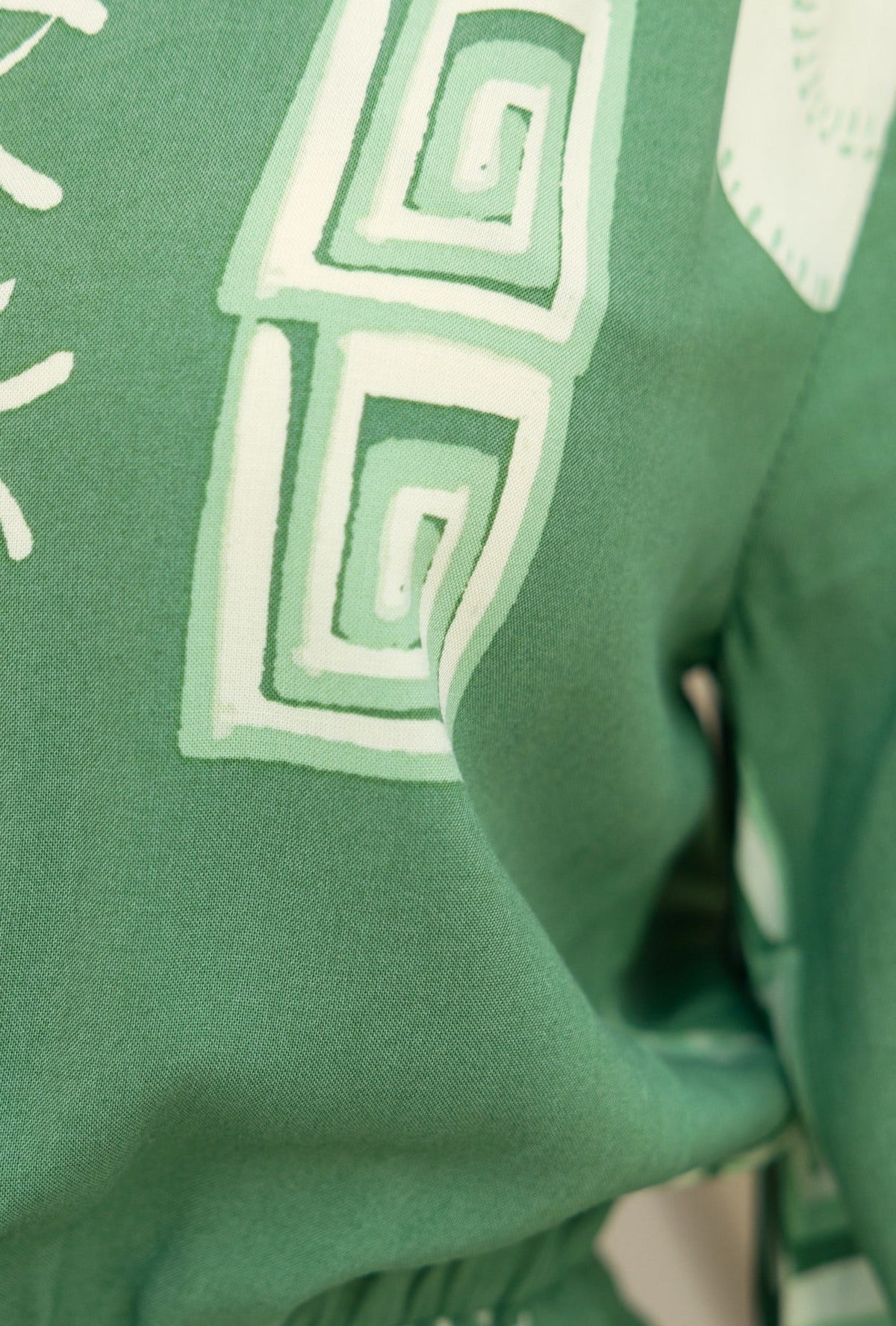Close-up of the Gratias Dress fabric with green pattern and intricate design details.