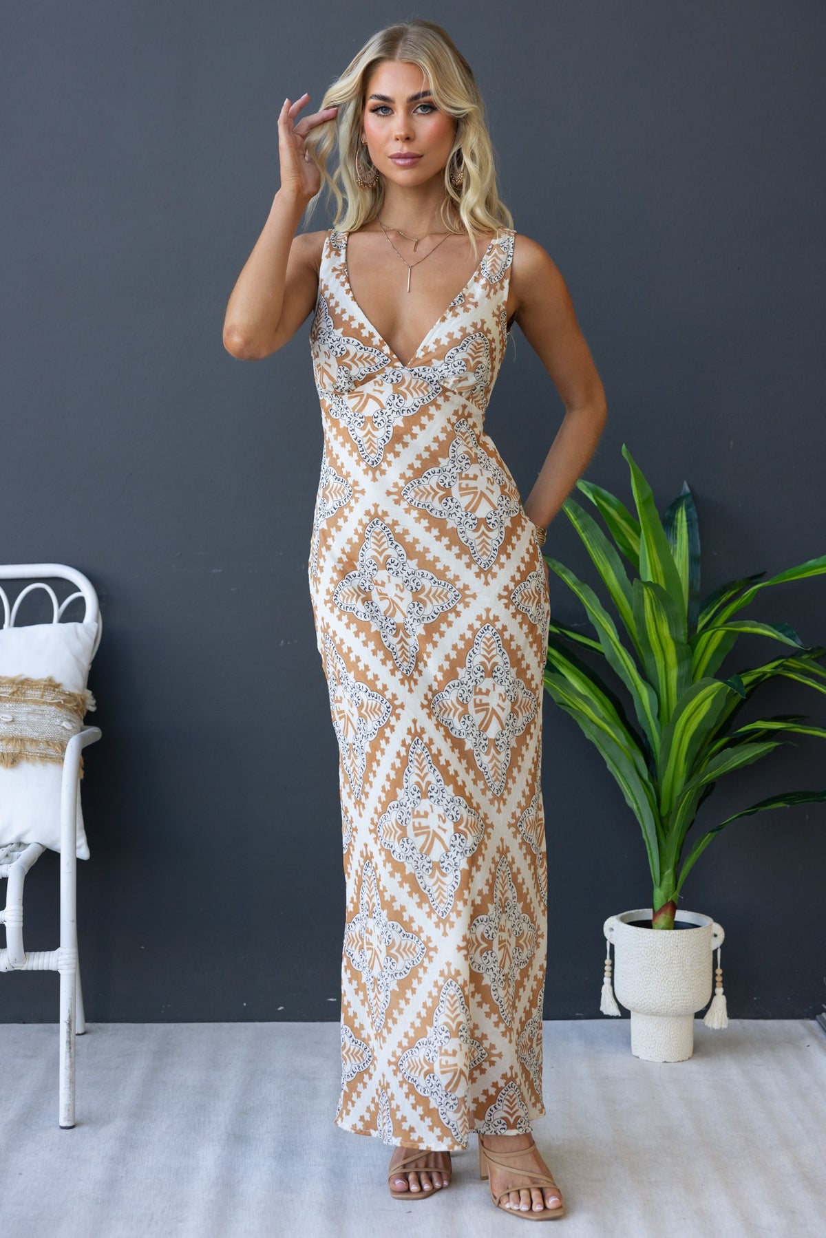 Woman modeling Mirabella Maxi Dress with V-neckline, intricate pattern, and chiffon material against a plain background.