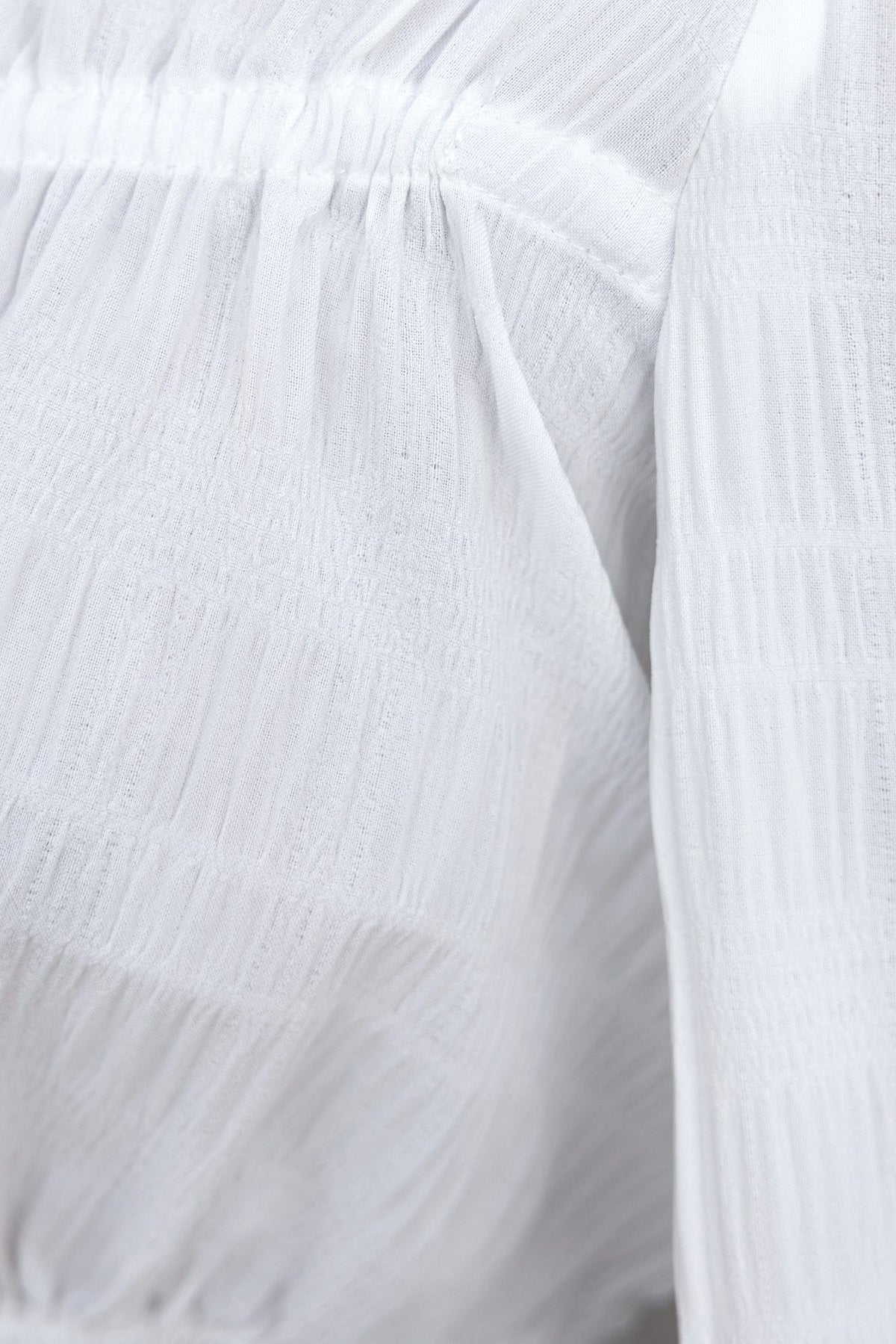 Close-up of the lightly textured white fabric of the Velzy Top showcasing its unique texture and design details.
