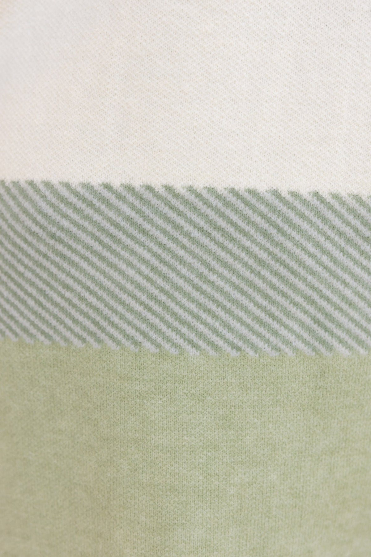 Close-up of soft knit fabric showcasing cream and green striped pattern, ideal for cozy cardigans.