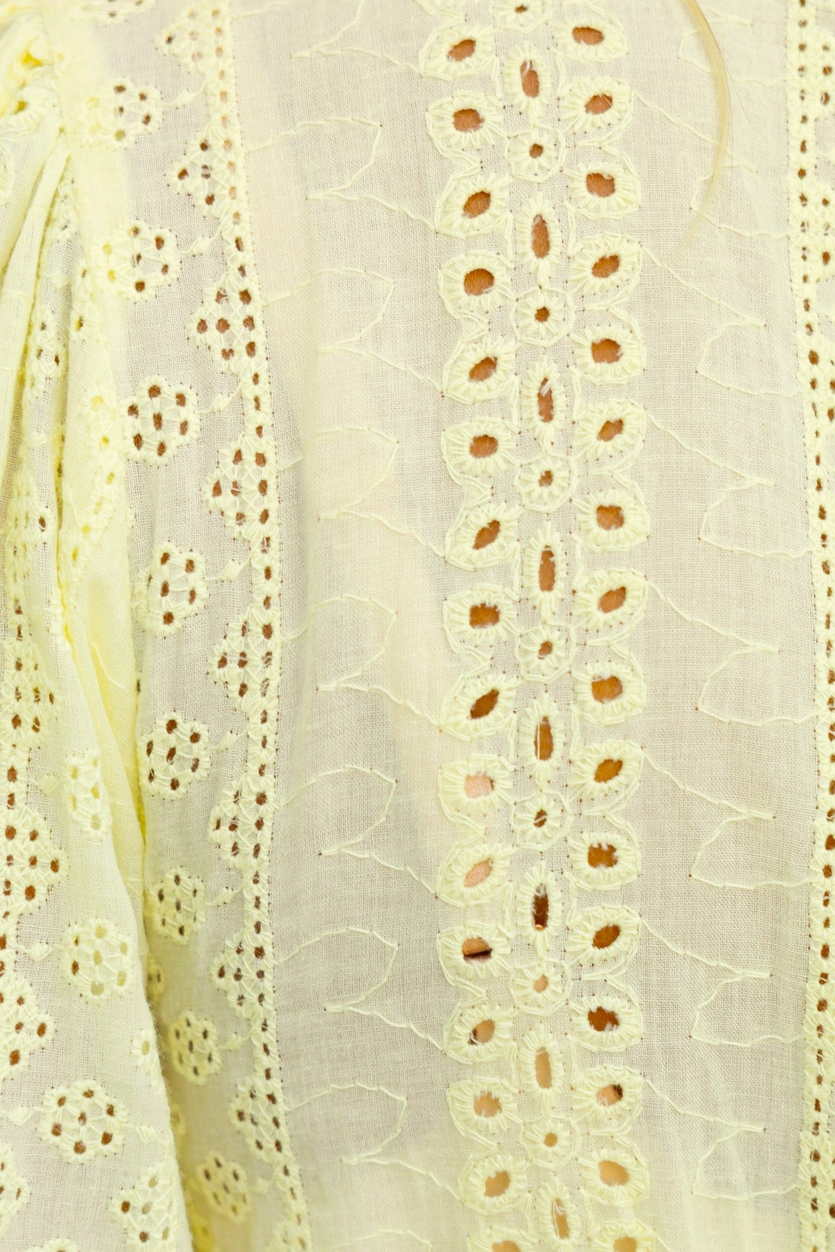 Close-up of Bonica Top featuring delicate Anglaise material with a V-neckline and button-up front in soft yellow.