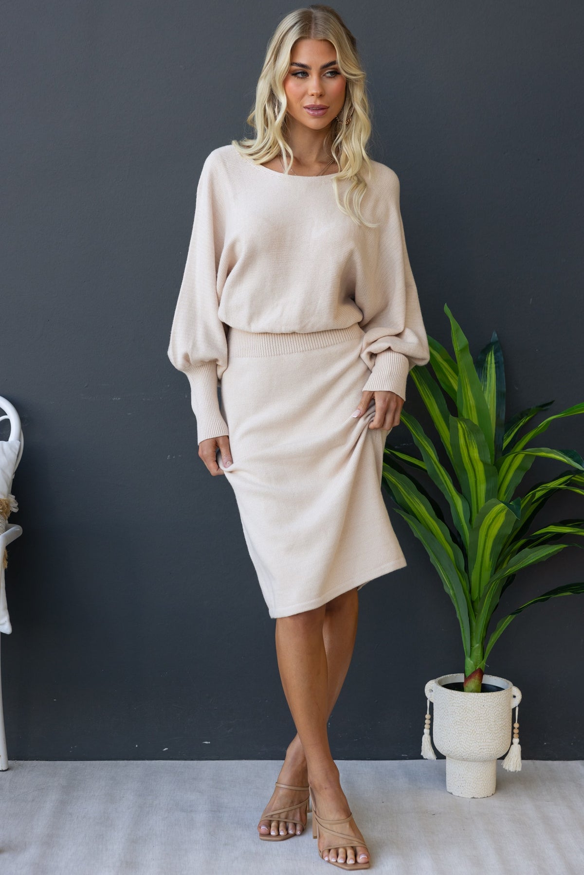 Model wearing the Jadala Midi Dress, featuring a boat neckline and relaxed fit, styled with a plant backdrop.