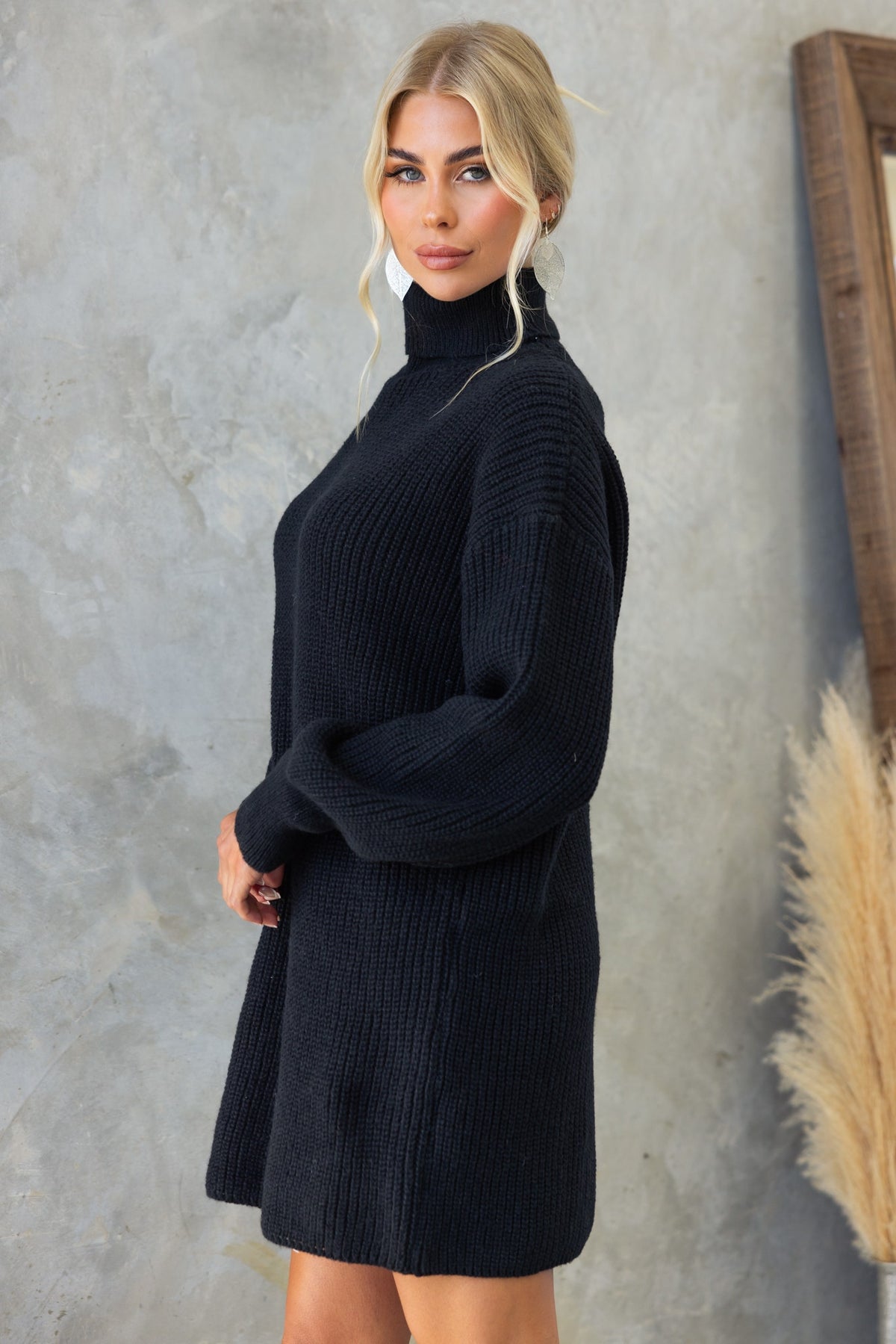 Model wearing the Whinnie Dress, a black knit turtleneck style dress, showcasing its relaxed fit and soft texture.