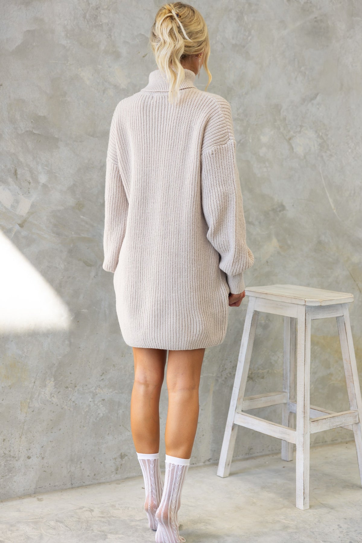 Back view of Whinnie Dress with turtle neckline in soft knit fabric, shown styled with knee-high socks.