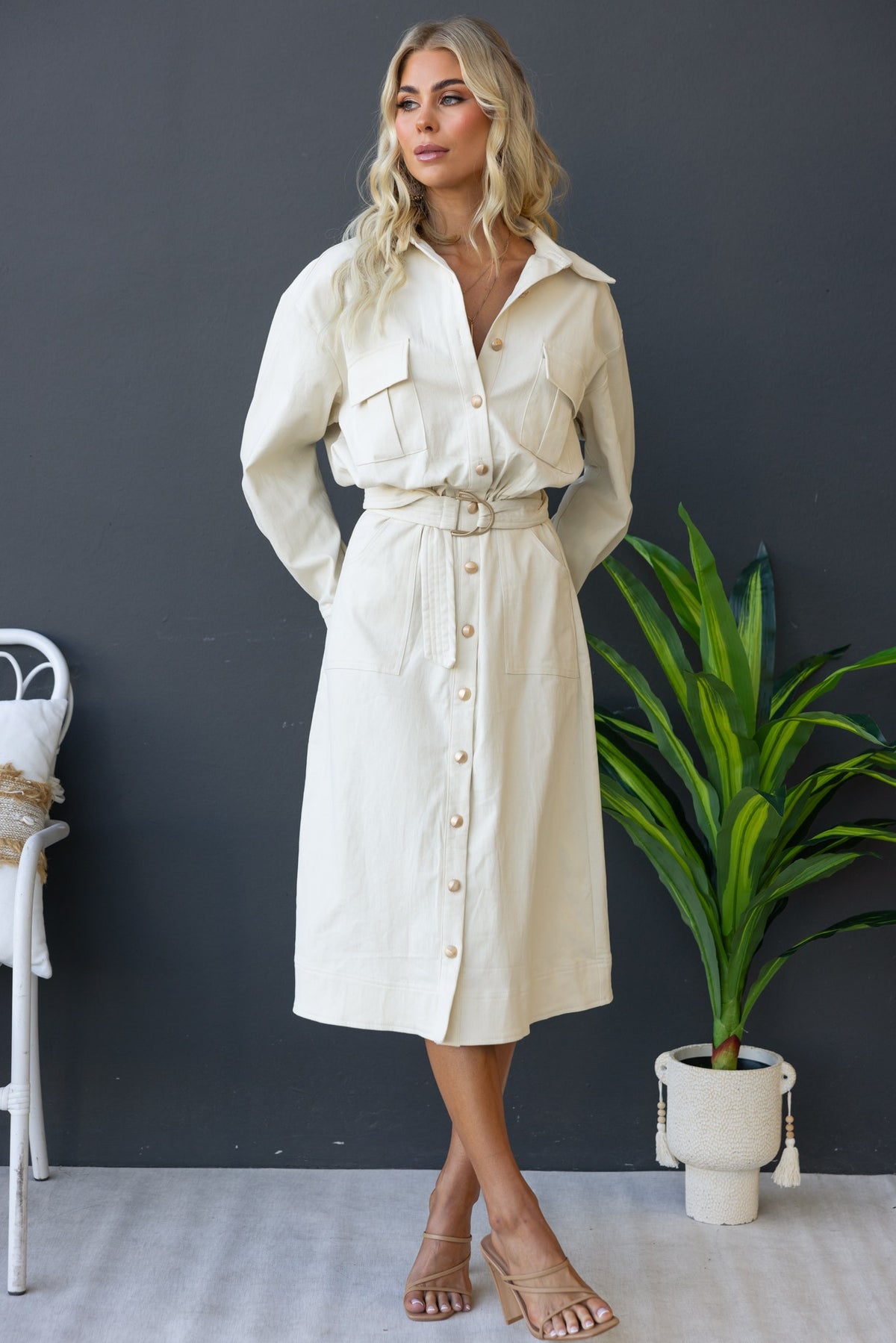 Model wearing a cream Ronin Denim Midi Dress with a button-up front, collar, and removable belt, styled with sandals.