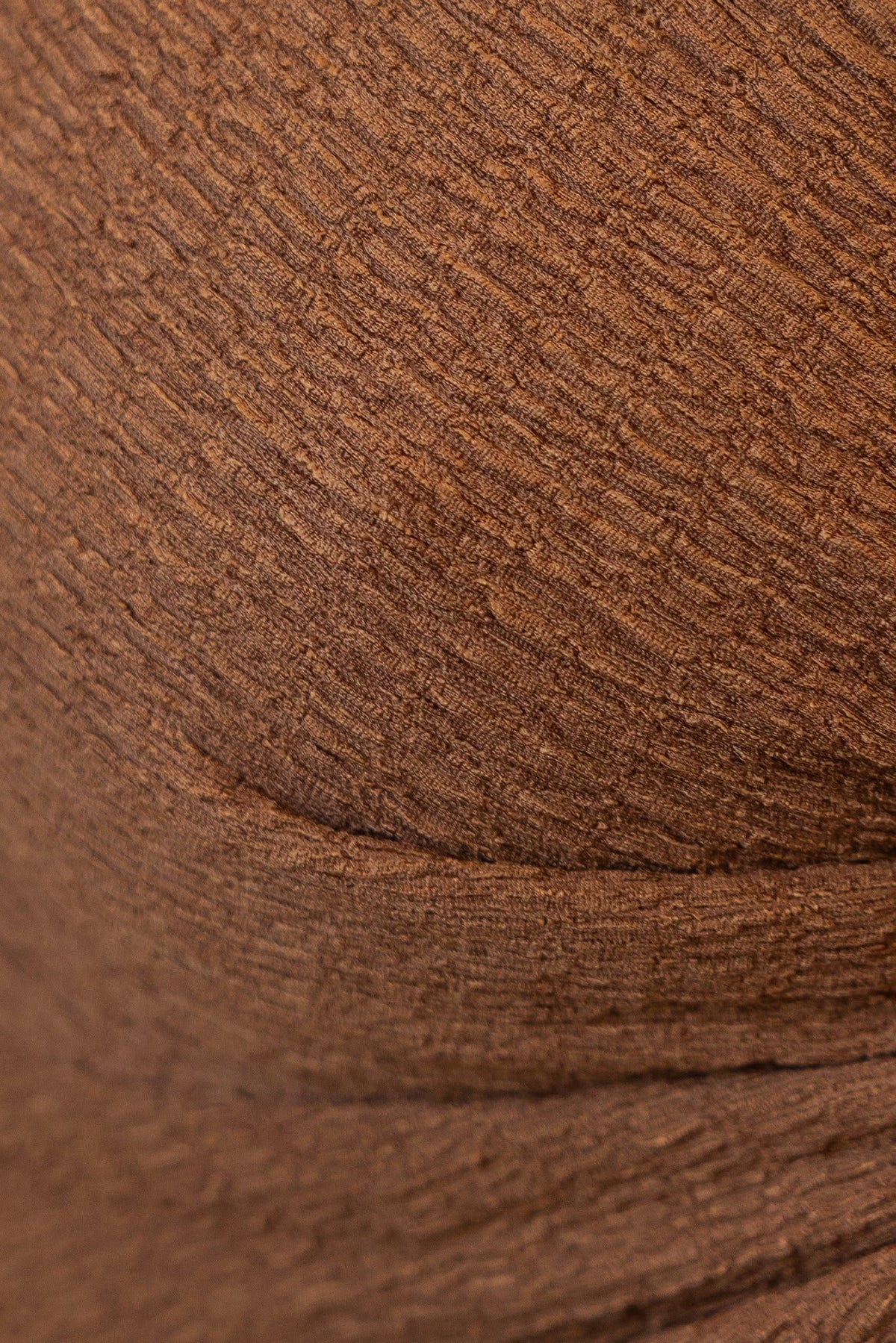 Close-up of textured brown fabric featuring a soft stretch, ideal for stylish adjustable tops.