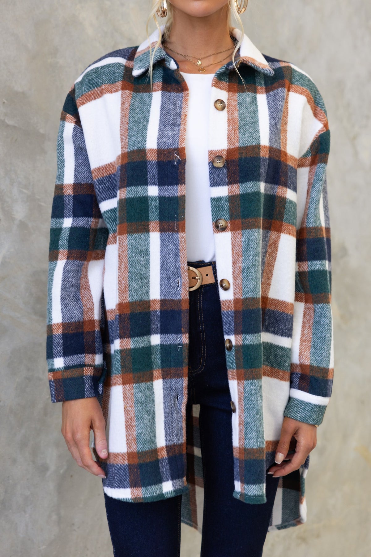 Braedyn shacket in plaid design, featuring a button-up front and high-low hem, styled with jeans and a white top.