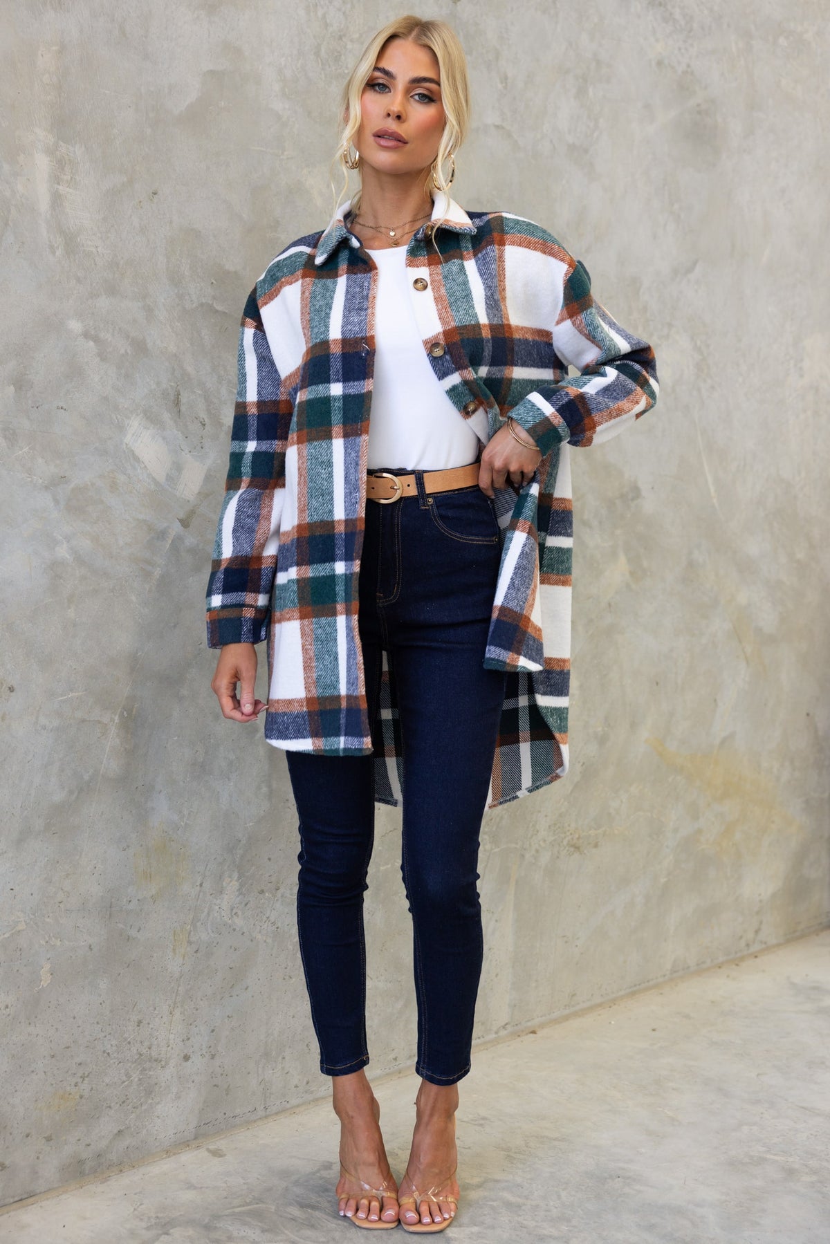 Model wearing the Braedyn Shacket, a stylish plaid button-up with a high-low hem, paired with jeans and sandals.