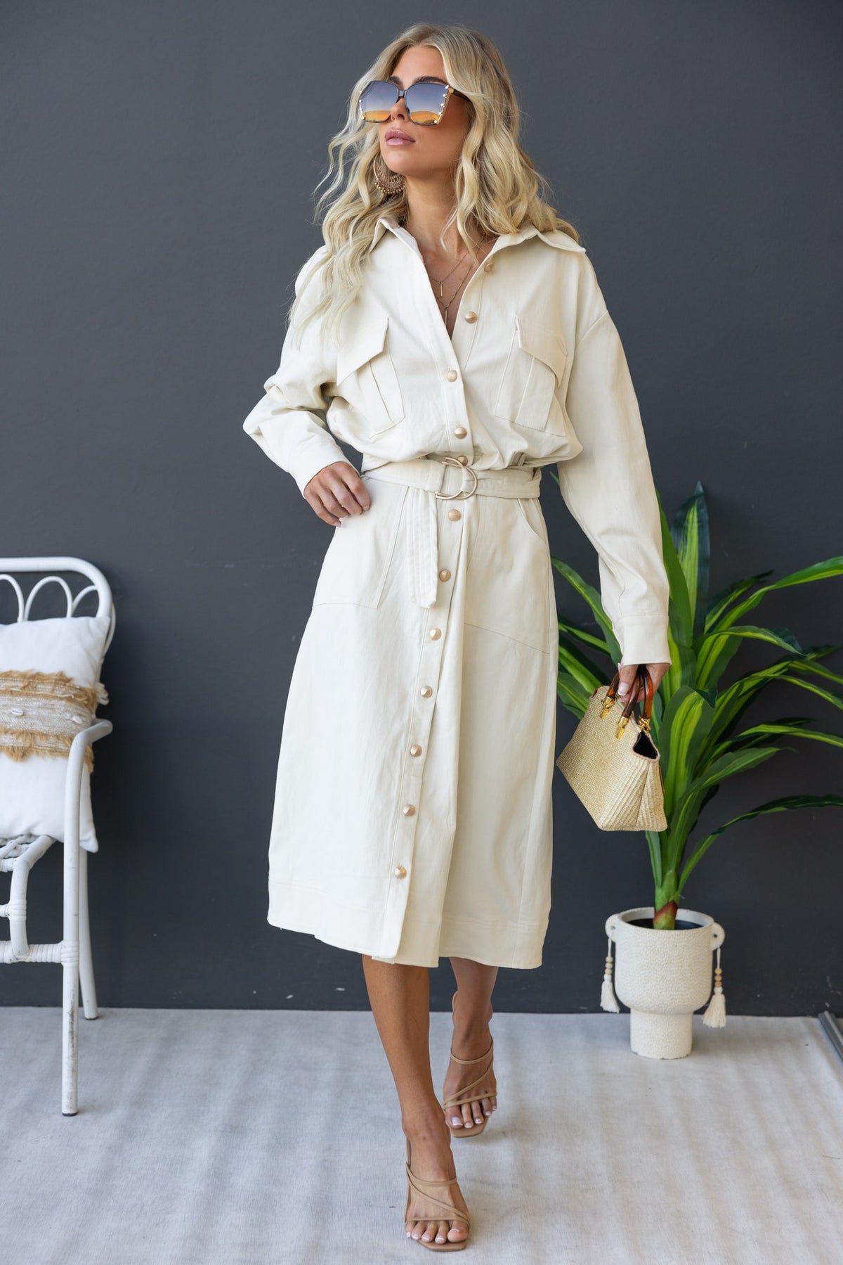 Stylish woman in cream Ronin Denim Midi Dress with button-up front, pockets, and removable belt, accessorized with sunglasses.